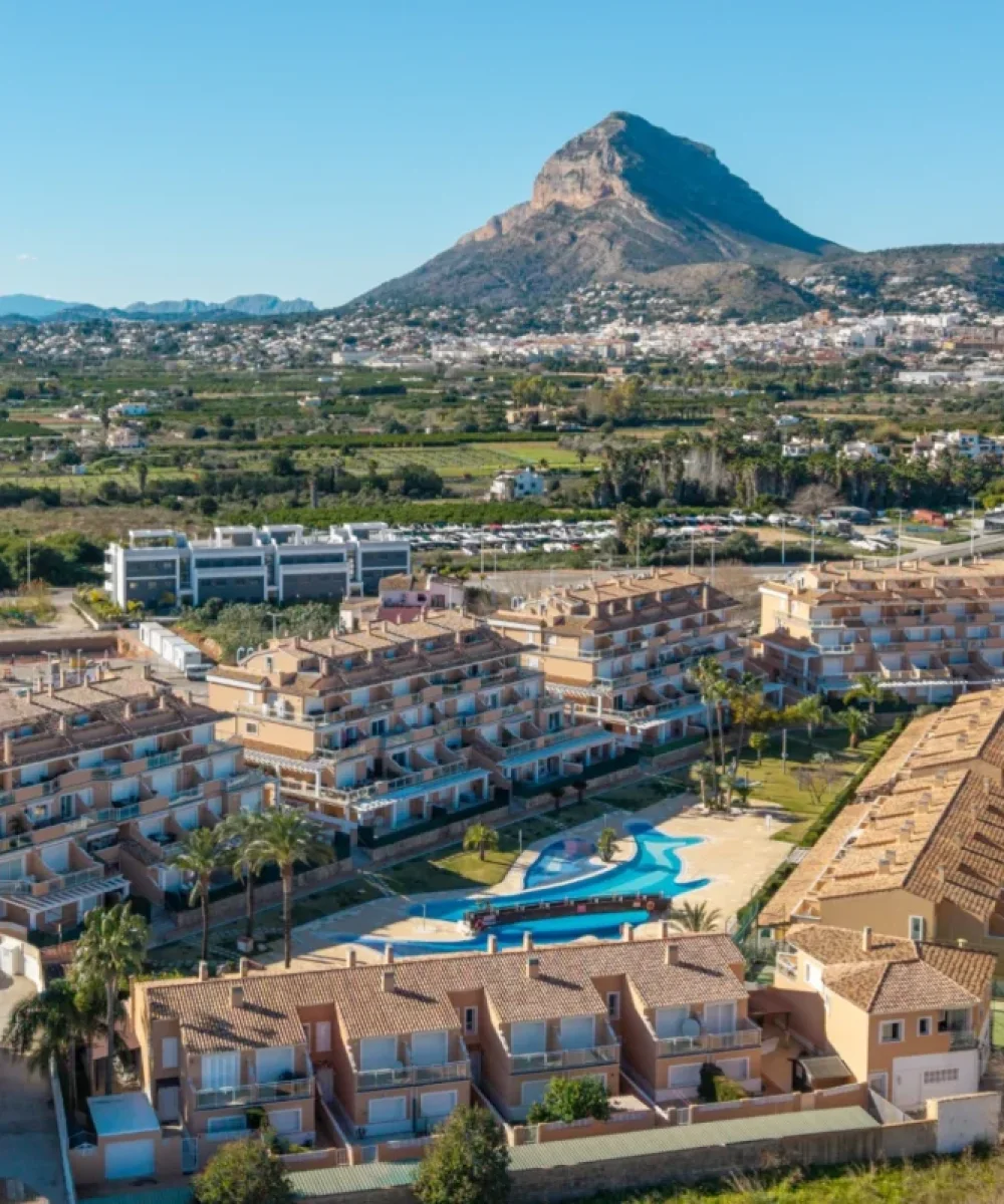 Vista aérea de apartamentos en Jávea con piscina y el Montgó al fondo.