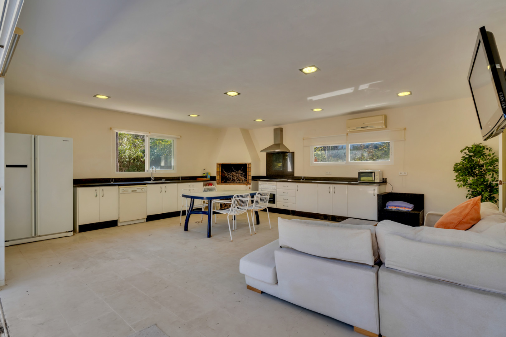 Amplia zona de barbacoa cubierta de 67 m² con cocina equipada, chimenea de obra y zona de estar, diseñada para el entretenimiento y con potencial para apartamento de invitados.