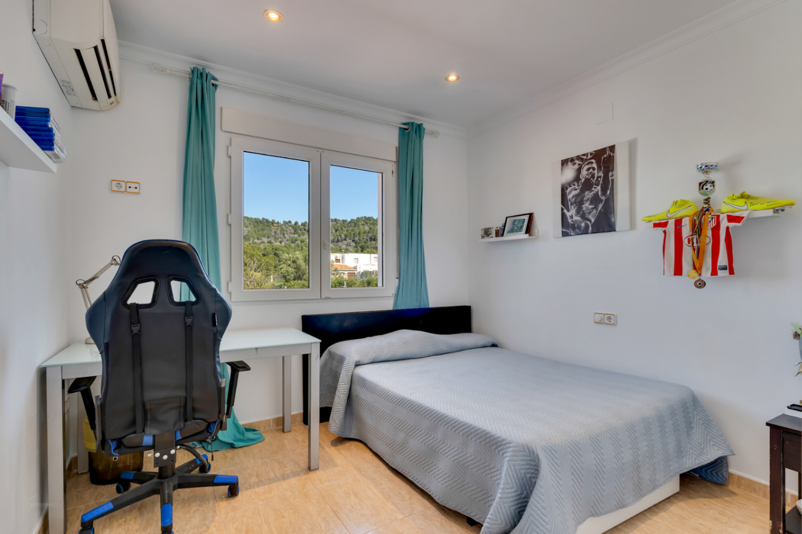 Dormitorio luminoso con zona de estudio, equipado con aire acondicionado, focos empotrados y ventana de PVC con vistas despejadas a la naturaleza de Jávea.