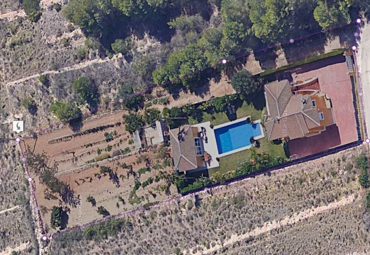 Vista aérea perimetral de la propiedad que muestra la distribución de la villa, la piscina de 15x6 metros y la extensa parcela rodeada de vegetación.