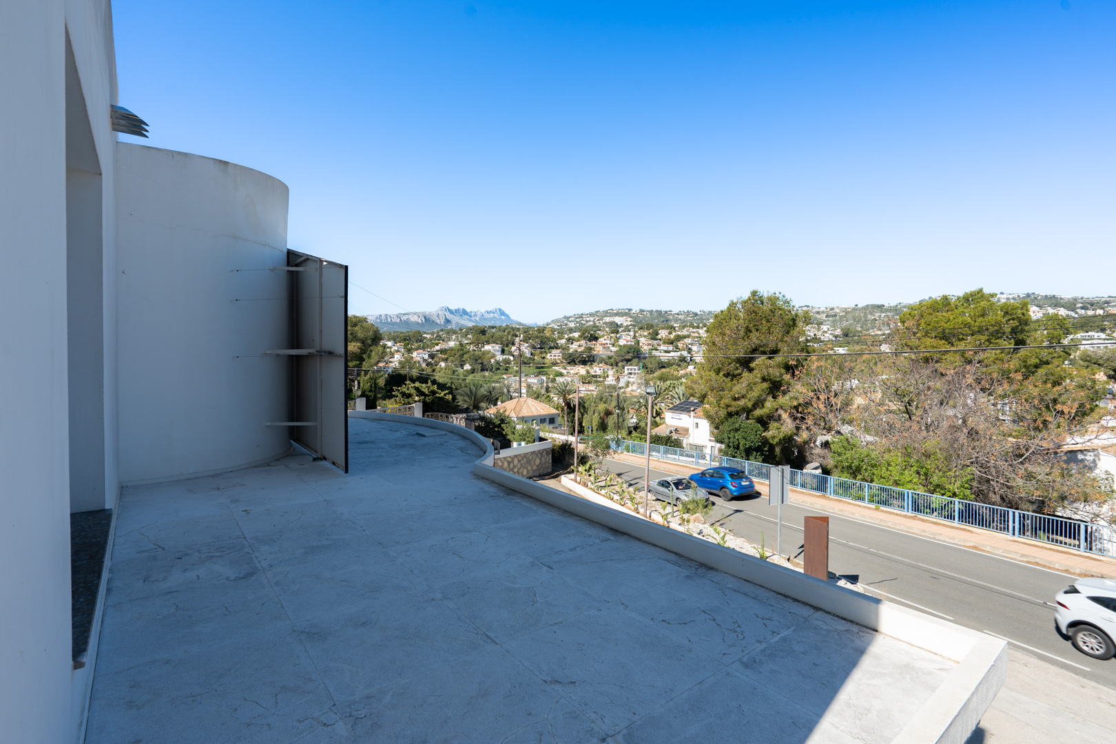 Amplia terraza con suelo de piedra clara y vistas despejadas a la Sierra de Bernia y al entorno residencial de Moraira.