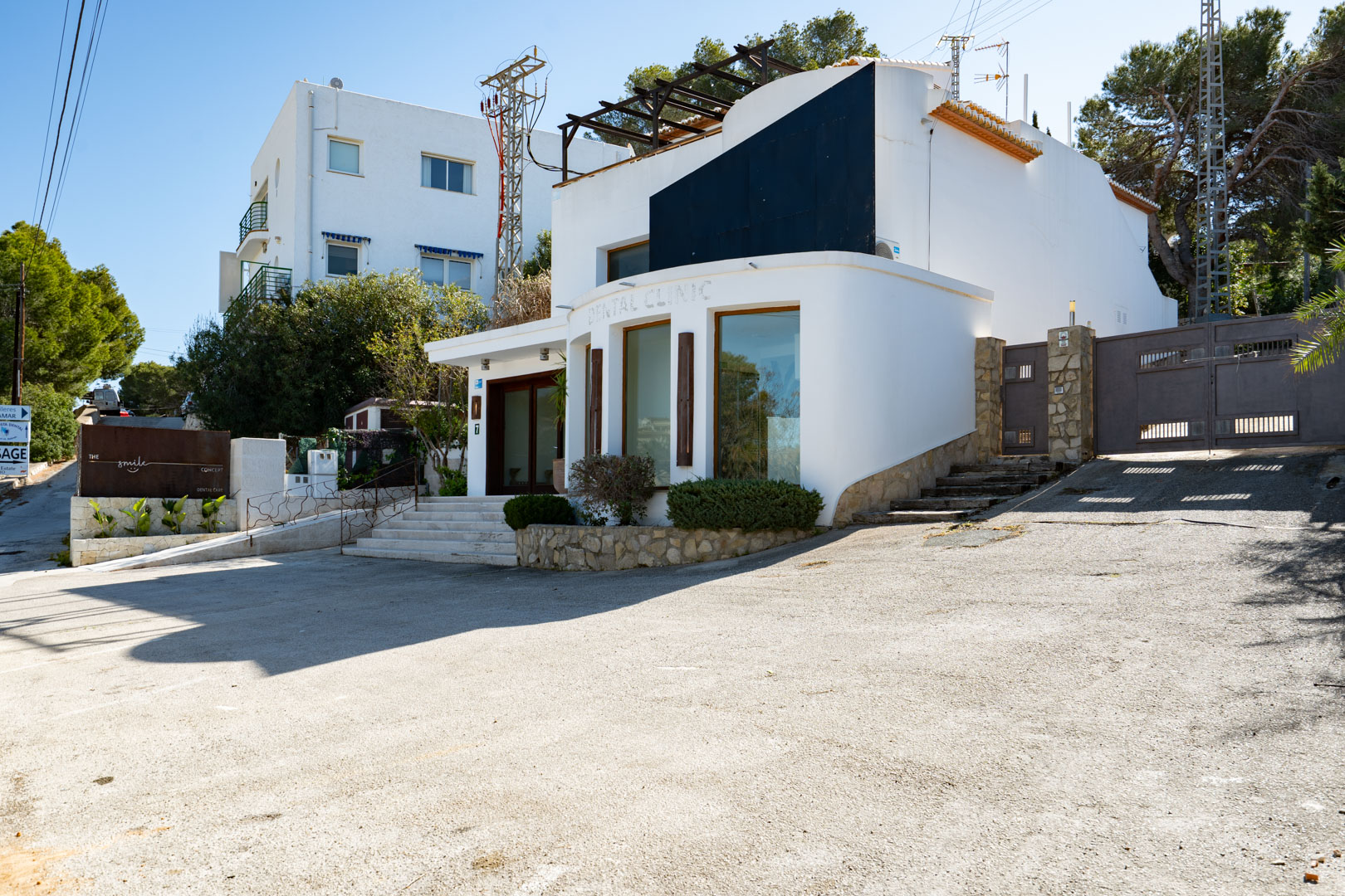 Fachada exterior de diseño contemporáneo con amplios ventanales, zona de aparcamiento frontal y acceso mediante puerta automática y escaleras de piedra.