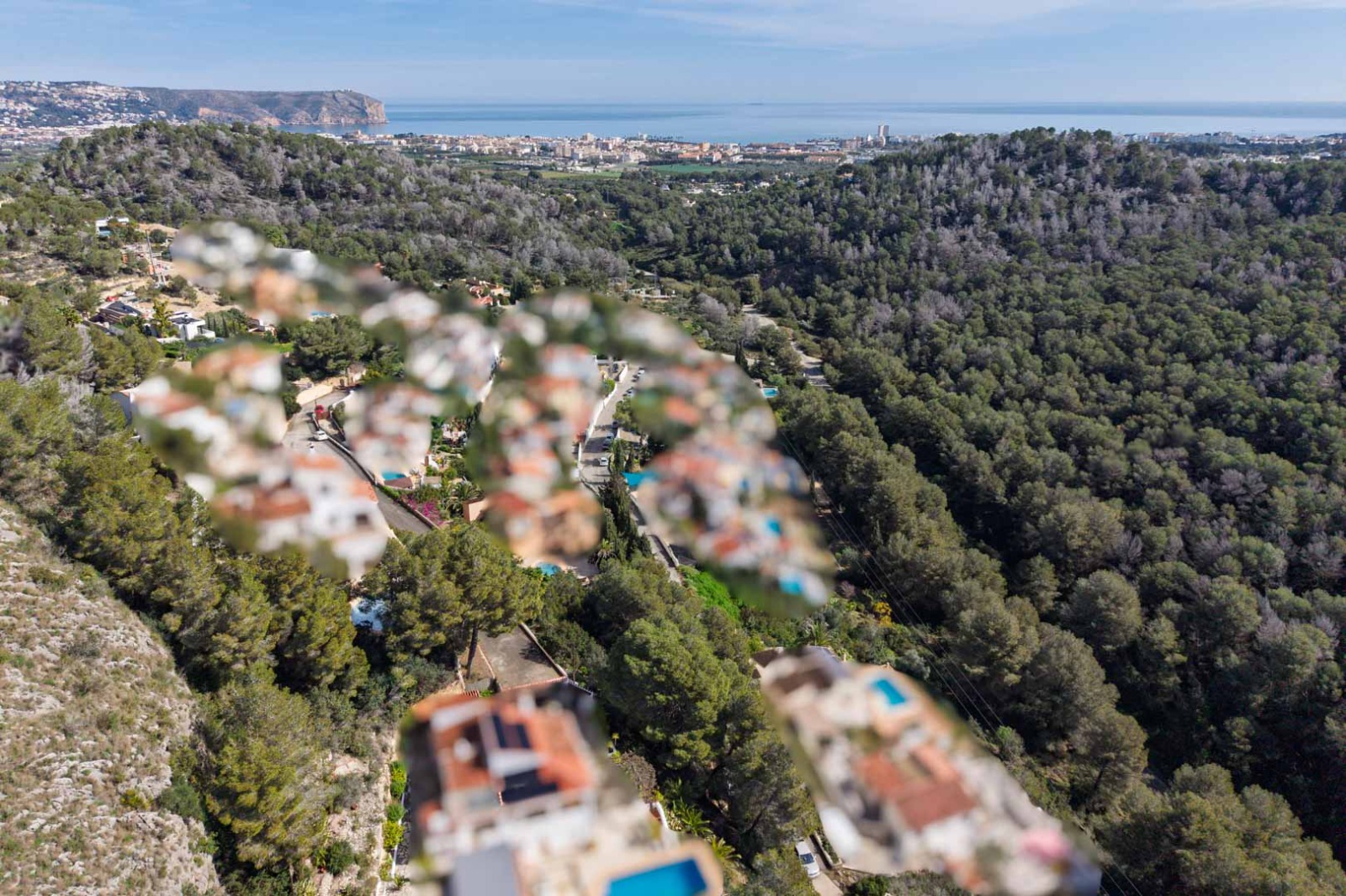 Vista aérea panorámica desde la urbanización Sol de Este hacia la costa de Jávea, destacando las colinas boscosas y el horizonte del mar Mediterráneo.