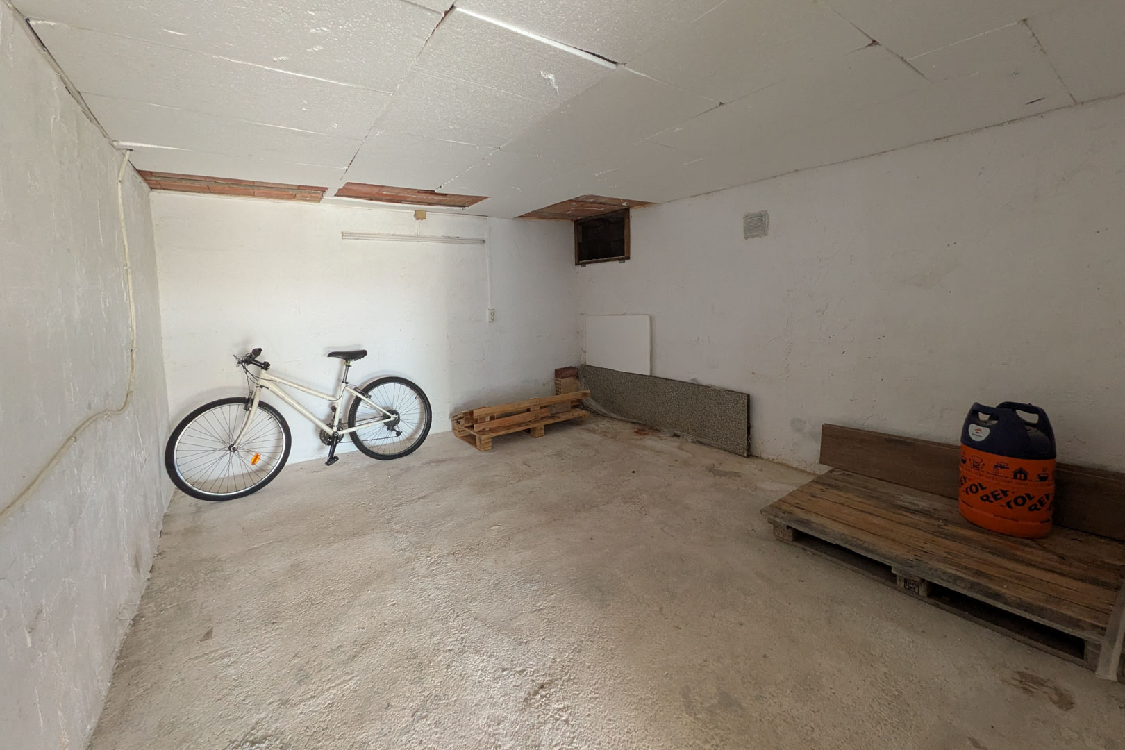 Trastero independiente con techos panelados, suelo de cemento y espacio versátil para almacenamiento de bicicletas o enseres.