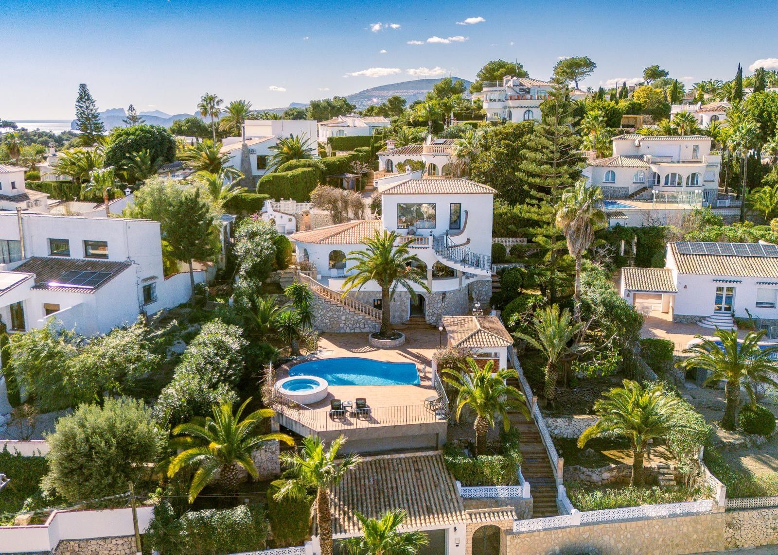 Vista aérea de la villa en Balcón al Mar con piscina, jacuzzi integrado y terrazas rodeadas de palmeras, destacando su arquitectura de niveles y vistas despejadas.