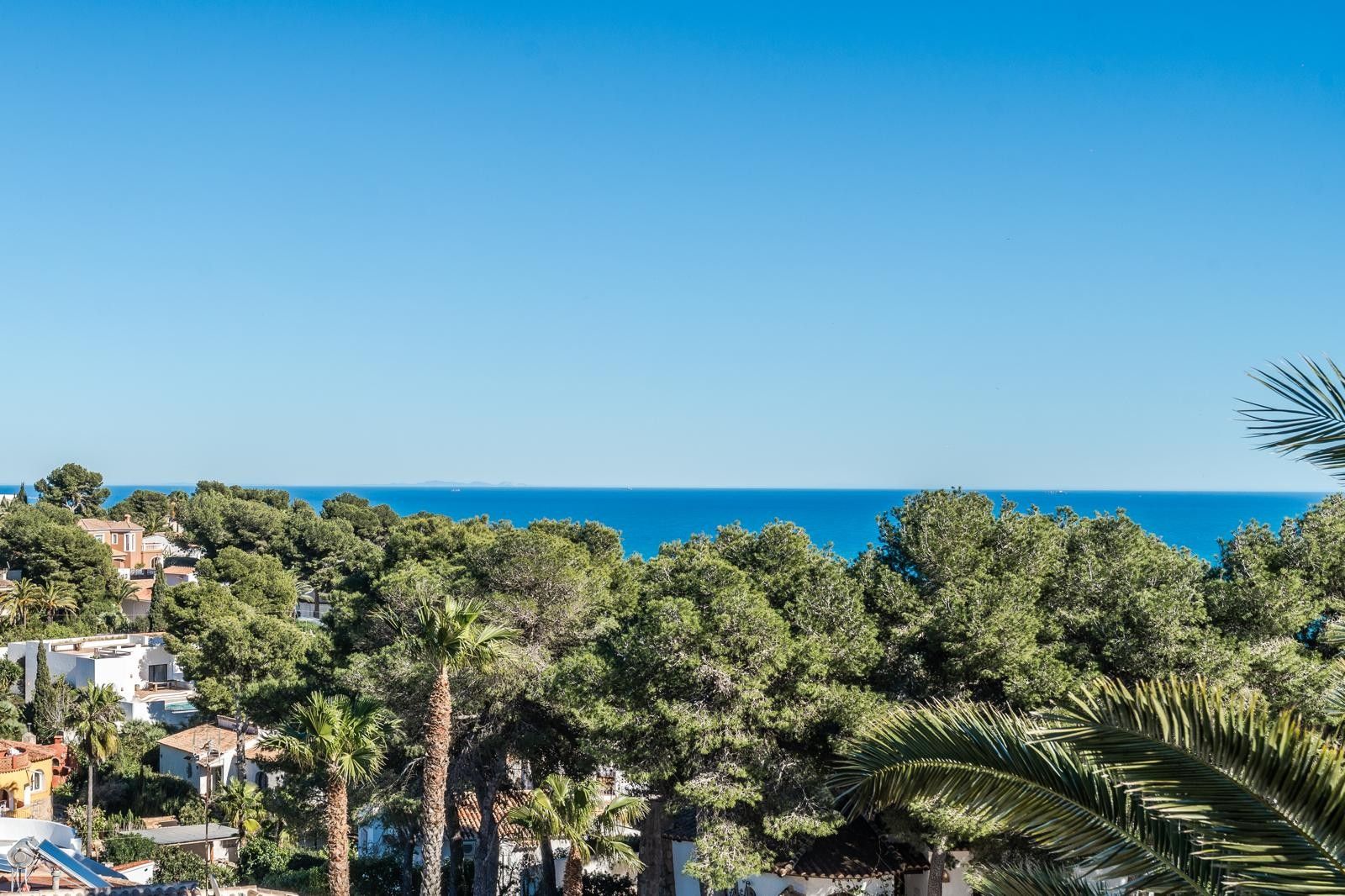 Vistas panorámicas al mar Mediterráneo desde la propiedad, rodeada de frondosos pinos y palmeras en la exclusiva zona de Balcón al Mar en Jávea.