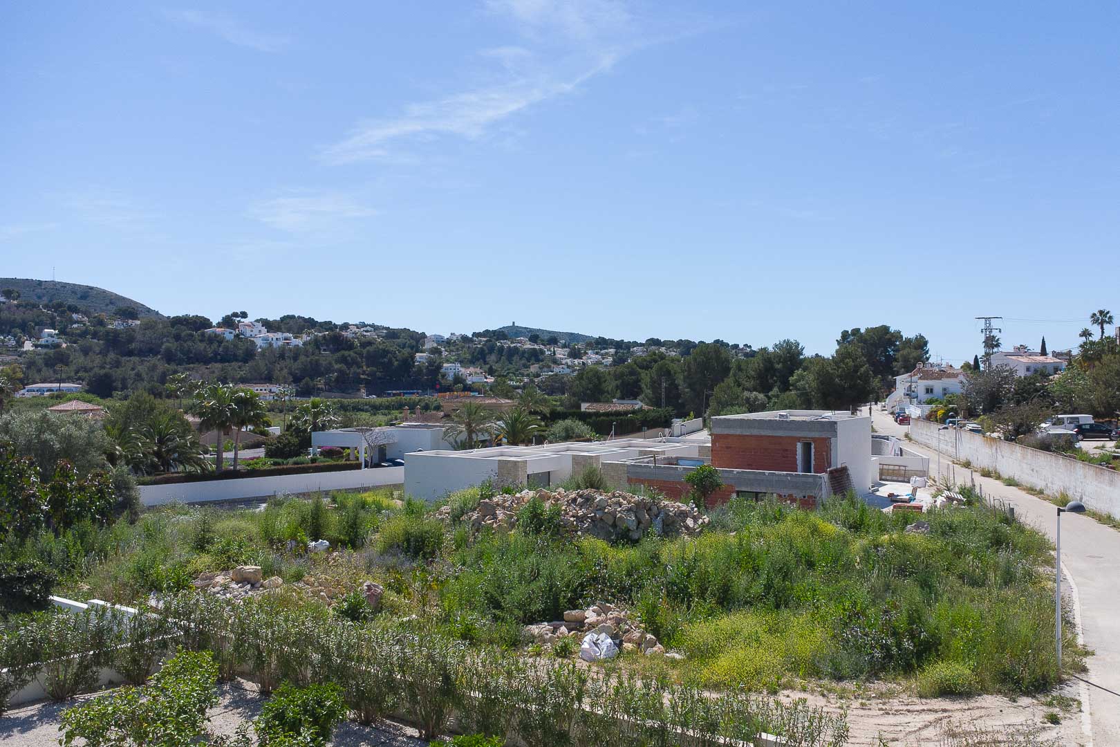 Vista exterior de la propiedad en fase de construcción, destacando su arquitectura moderna de líneas rectas integrada en el paisaje natural de Moraira.