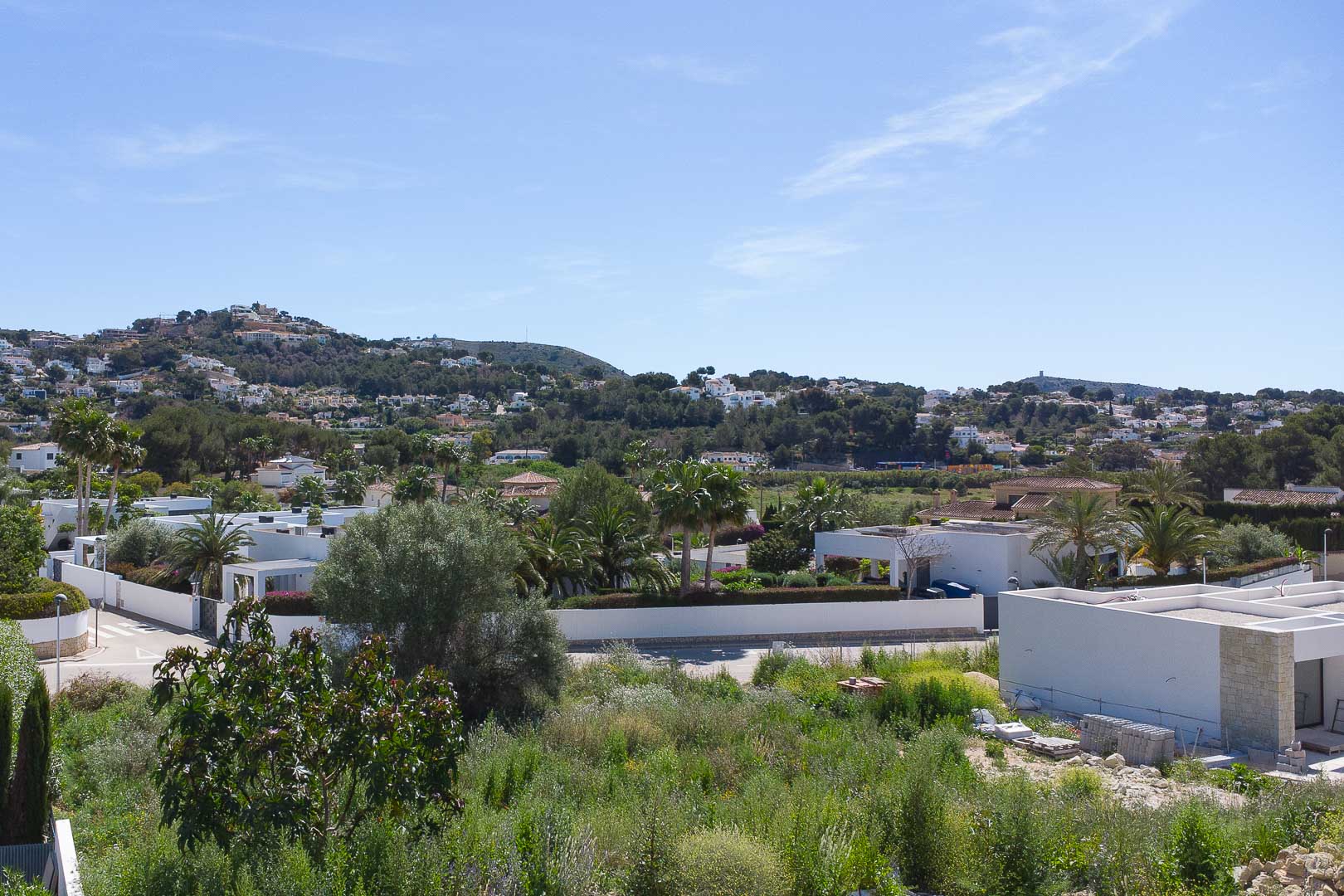 Vistas panorámicas desde la propiedad hacia el entorno residencial de Moraira, destacando la arquitectura blanca mediterránea y la vegetación local bajo un cielo despejado.