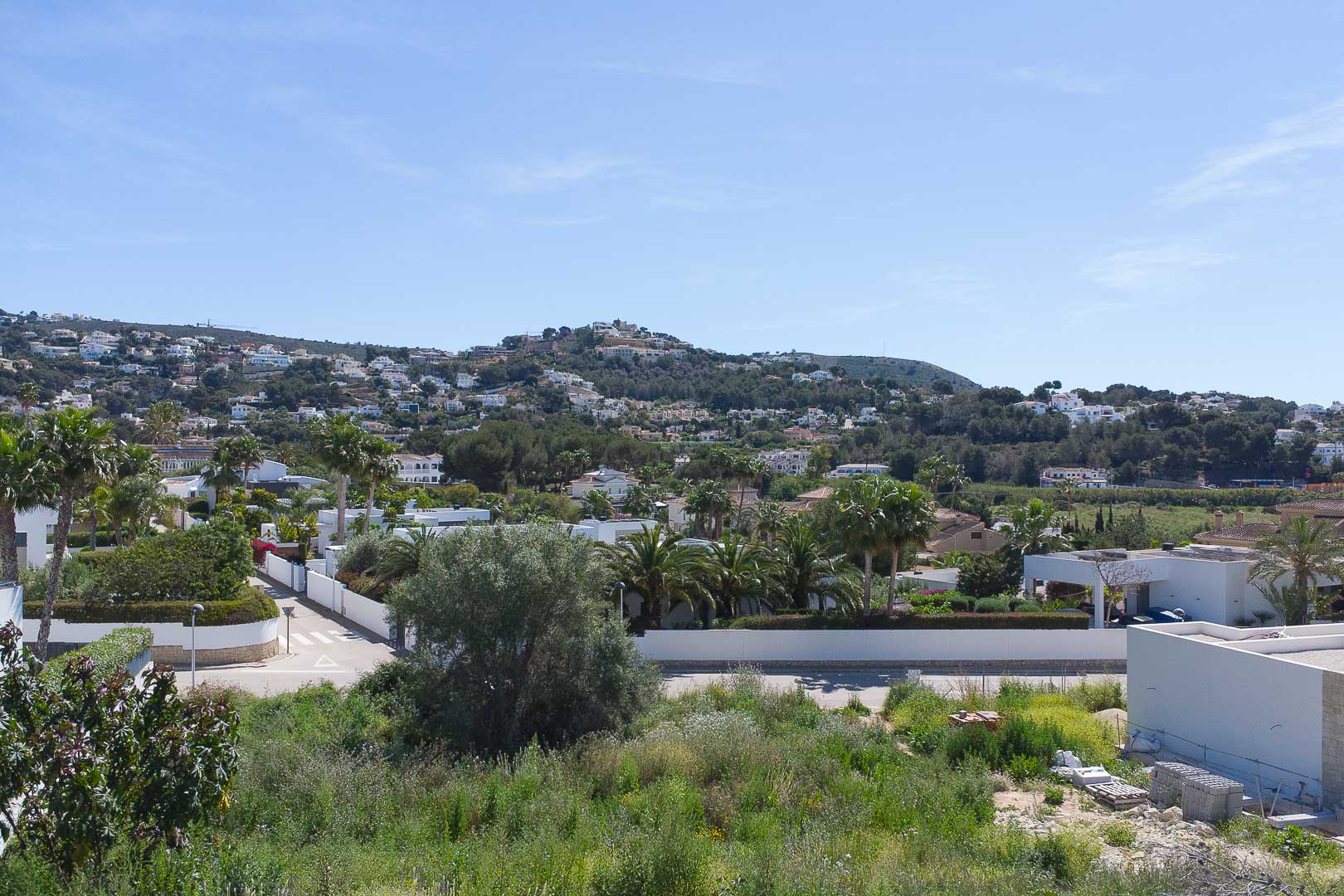 Vistas panorámicas desde la propiedad hacia el paisaje residencial de Moraira, con colinas verdes y arquitectura mediterránea bajo un cielo despejado.