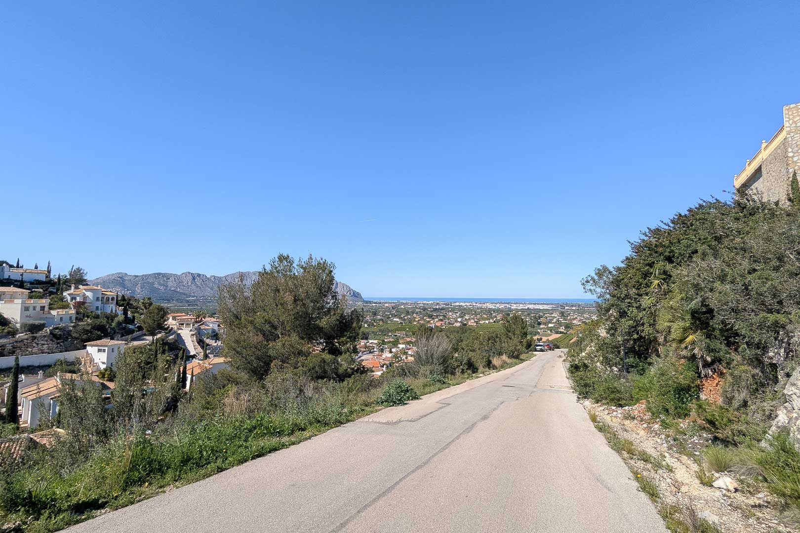 Acceso a la villa con vistas panorámicas de Pedreguer y el mar Mediterráneo en el horizonte bajo un cielo despejado.