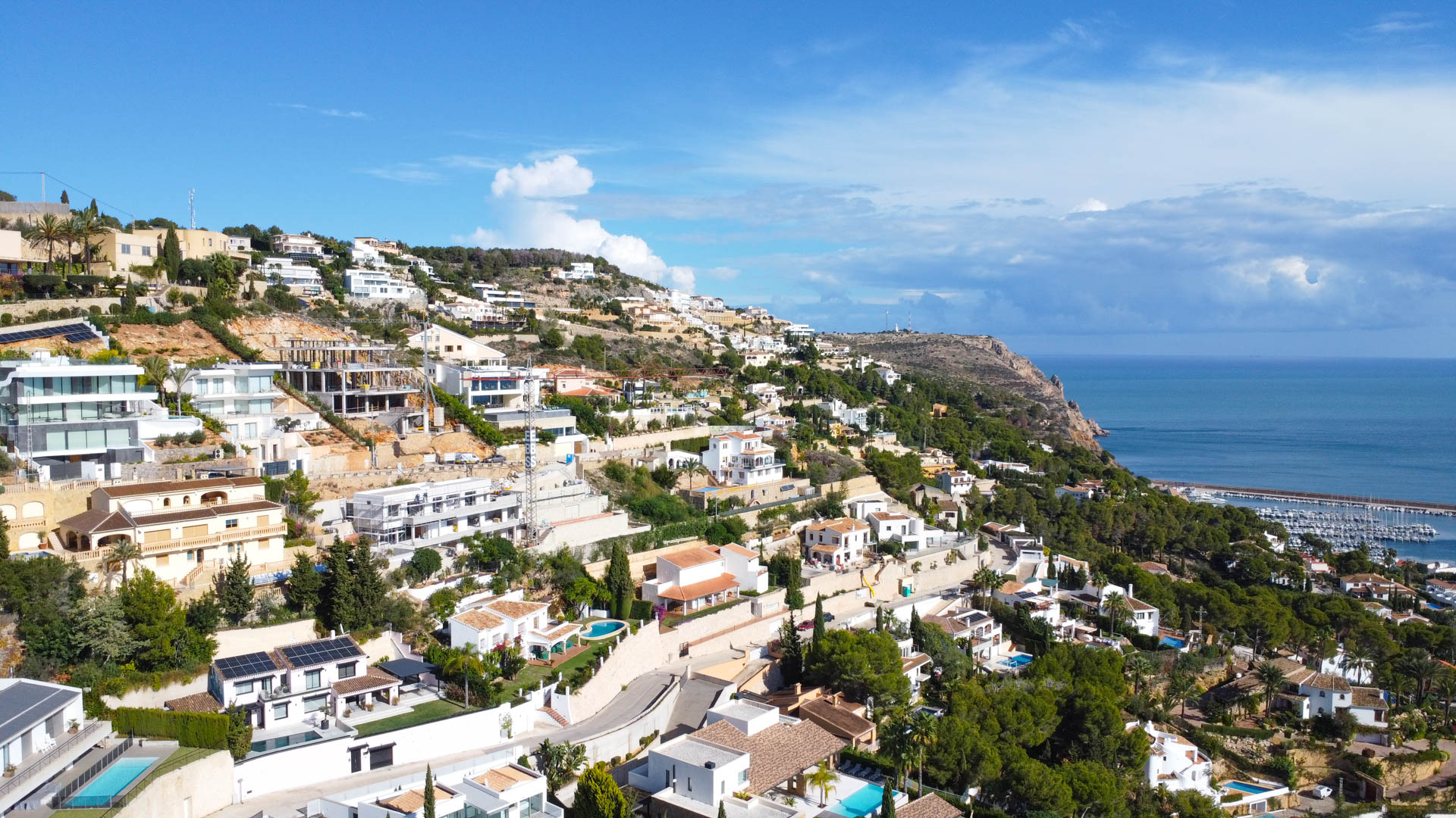 Vista aérea de la exclusiva urbanización La Corona en Jávea, destacando la ladera orientada al sur con vistas panorámicas al mar y al puerto.