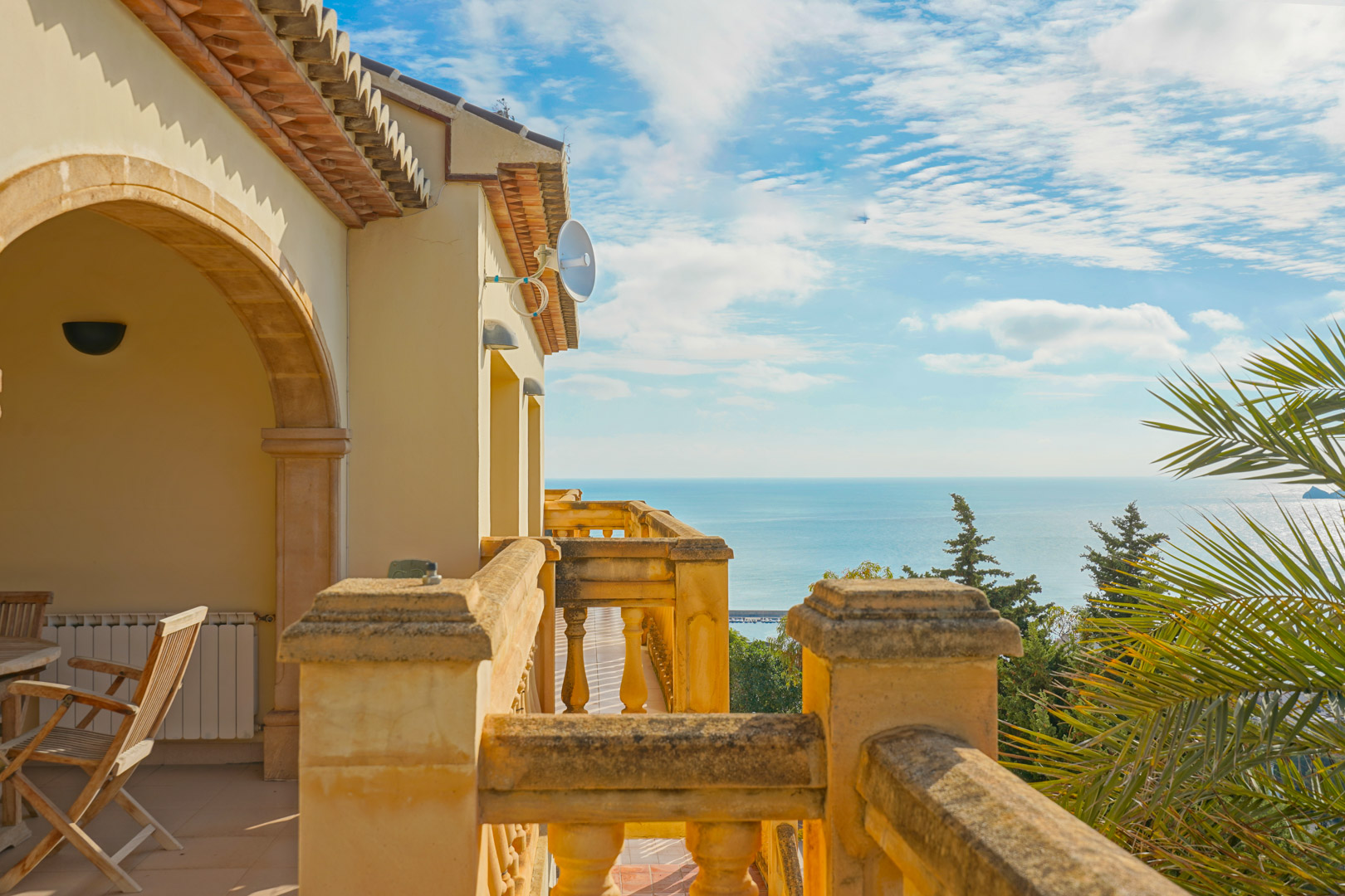 Terraza superior con balaustrada de piedra y arcos tradicionales, ofreciendo vistas despejadas al mar Mediterráneo y al horizonte de Jávea bajo un cielo despejado.