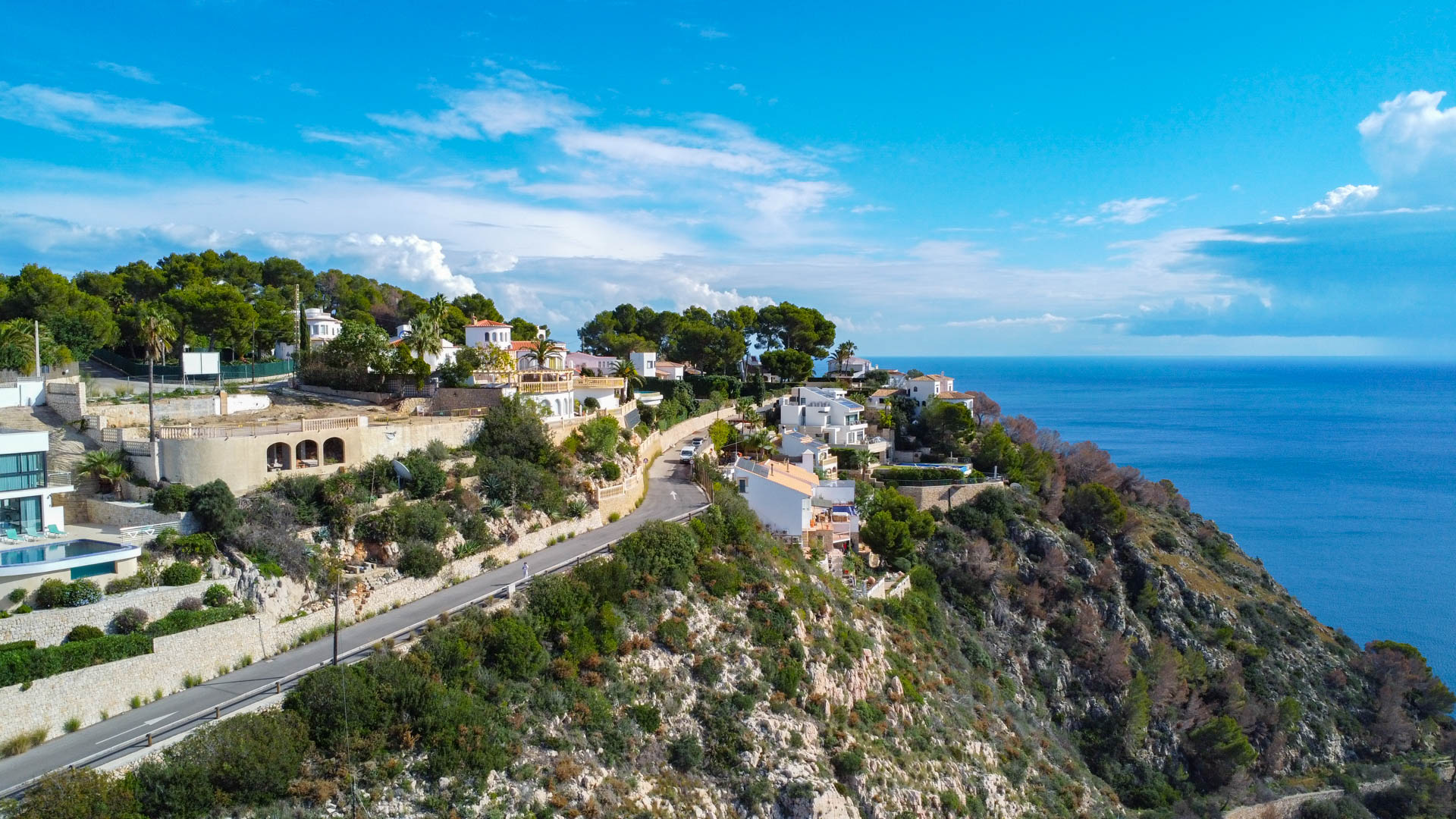 Vista aérea de la parcela elevada en Granadella, mostrando el acceso por carretera asfaltada y las vistas panorámicas al mar Mediterráneo y acantilados.