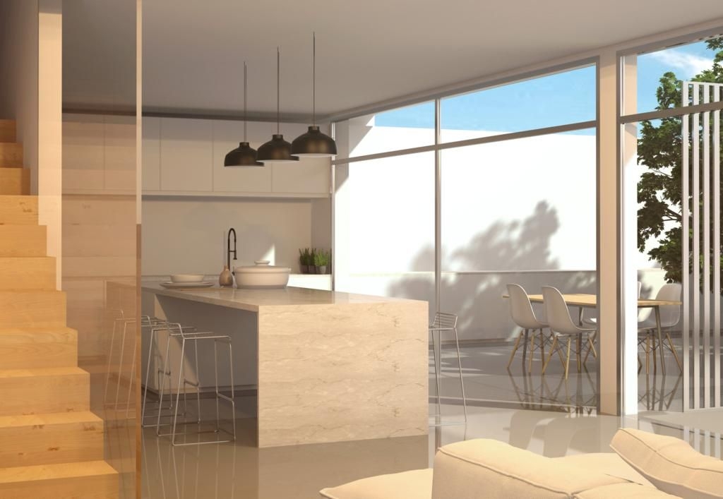 Cocina de concepto abierto con isla de acabado en piedra, lámparas colgantes negras y amplios ventanales que conectan con la terraza exterior y el comedor.