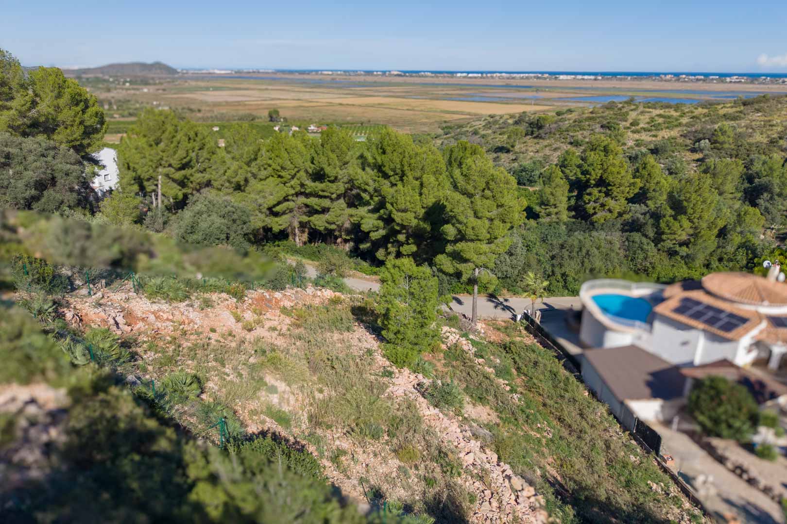 Parcela elevada con vallado perimetral que ofrece vistas despejadas al Parque Natural de la Marjal de Pego y al mar Mediterráneo.