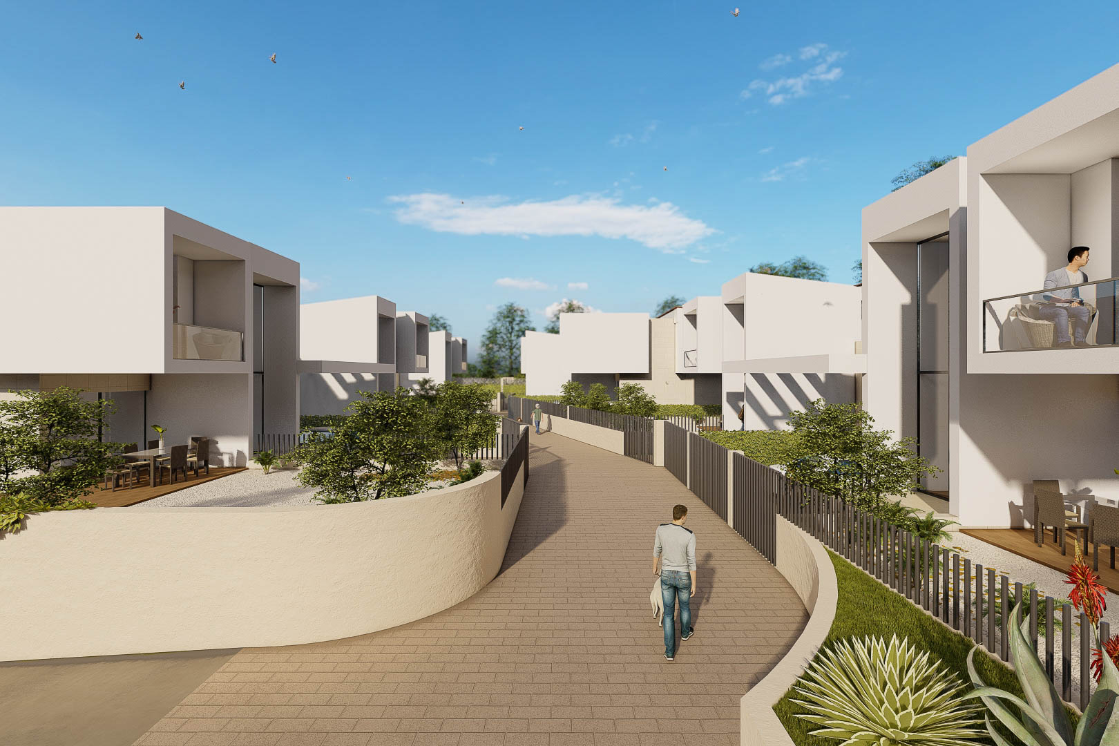 Vista exterior del complejo con villas blancas de diseño cúbico, viales pavimentados y jardines privados con vegetación mediterránea y cerramientos metálicos.