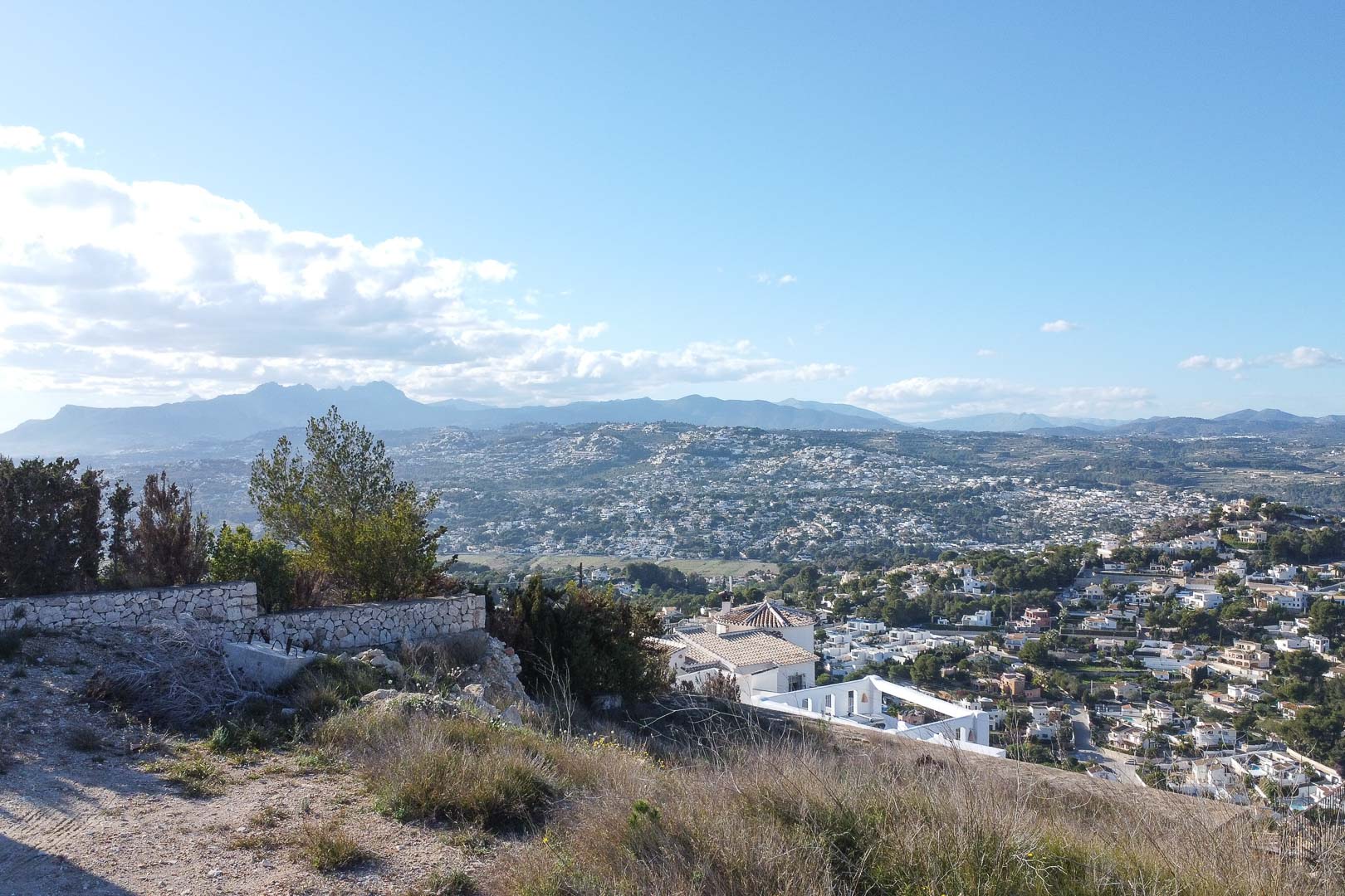 Vista panorámica de Moraira desde una colina, mostrando el paisaje urbano y las montañas en la distancia.