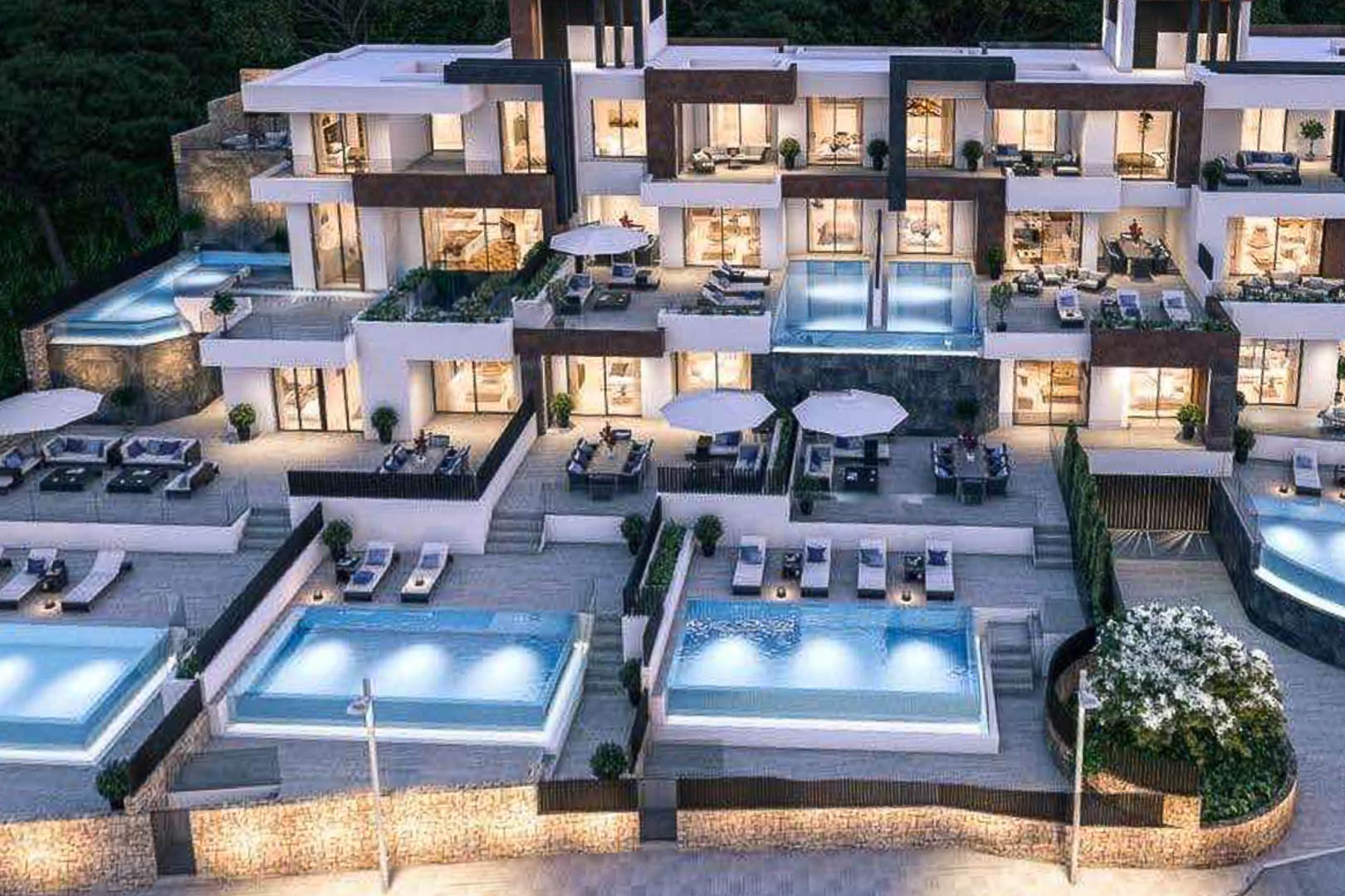 Vista exterior de un complejo residencial moderno con terrazas escalonadas, piscinas privadas iluminadas y fachadas que combinan piedra natural con acabados blancos.