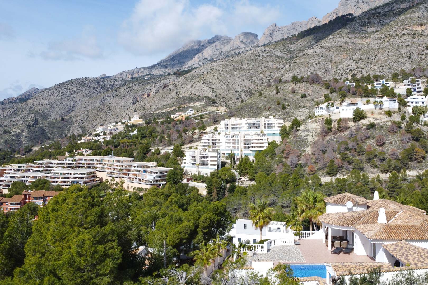 Vista aérea de la villa con tejado de teja y piscina privada, destacando su ubicación privilegiada bajo las crestas de la Sierra de Bernia.