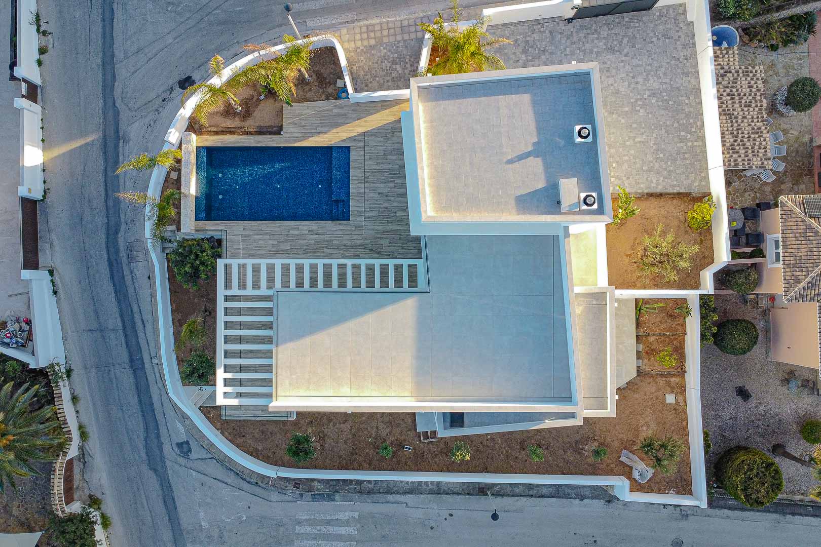 Vista aérea de villa moderna en Benimeit con piscina azul y terrazas de baldosas grises.