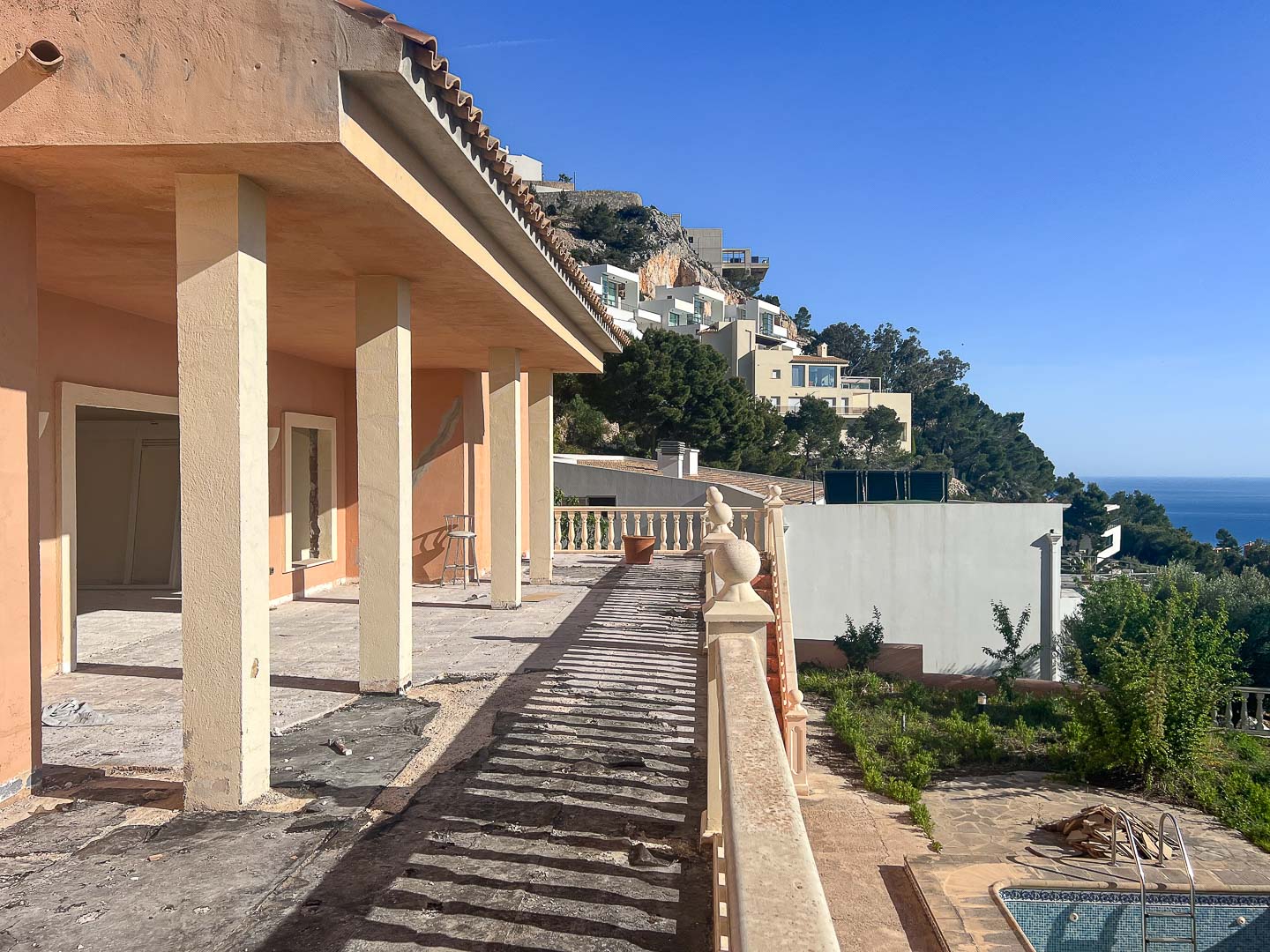 Terraza exterior en proceso de renovación con columnas estructurales, balaustrada clásica y vistas panorámicas hacia la costa de Altea y el mar Mediterráneo.