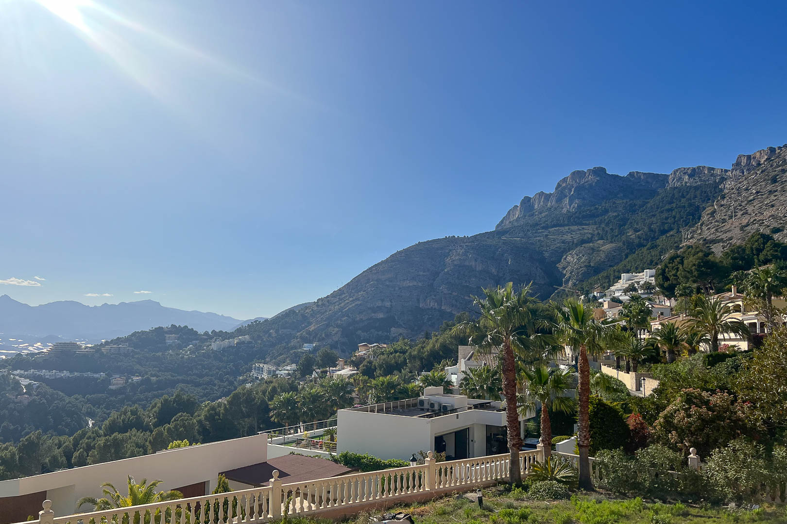 Vista panorámica desde Altea Hills que muestra la Sierra de Bernia, villas blancas integradas en la montaña y vegetación mediterránea bajo un cielo despejado.