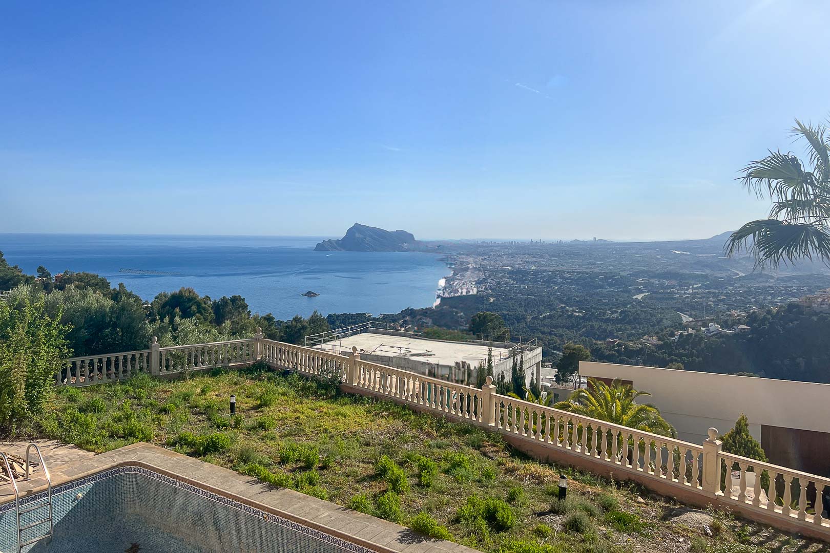 Vistas panorámicas al mar Mediterráneo y al Peñón de Ifach desde la zona exterior con balaustrada de piedra y jardín.