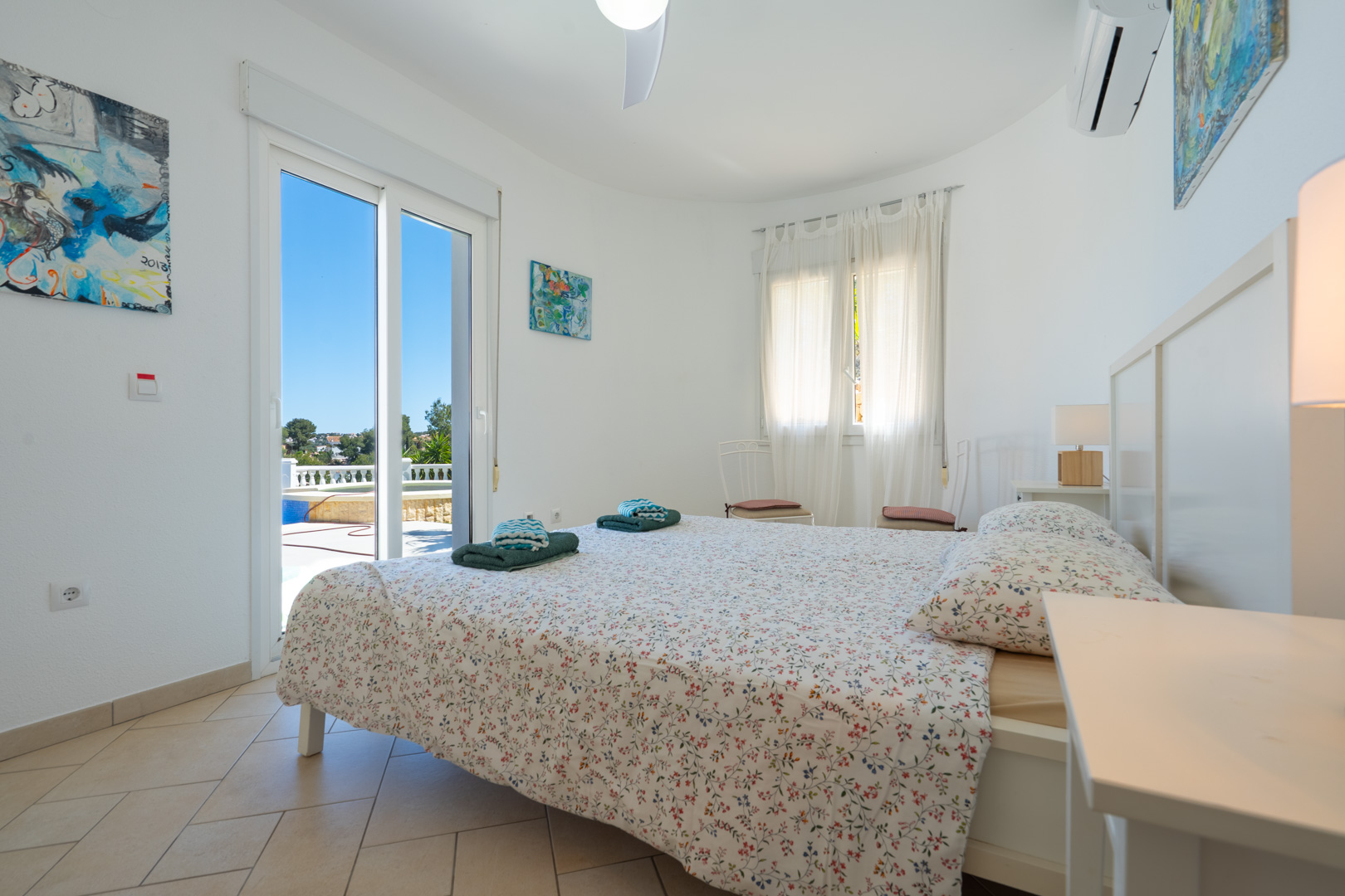 Dormitorio luminoso con acceso directo a la terraza y piscina, equipado con aire acondicionado, suelos de gres y ventanales de PVC.