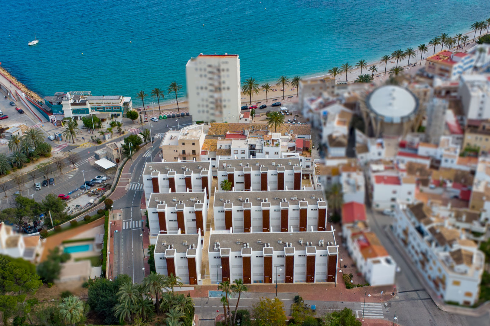 Vista aérea del complejo residencial junto al puerto de Jávea, destacando su arquitectura moderna y la proximidad inmediata al mar Mediterráneo y al paseo marítimo.