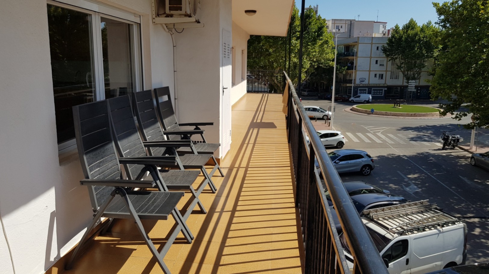 Terraza alargada con suelo cerámico en tono ocre, equipada con sillas plegables y vistas despejadas al entorno urbano y arbolado de Jávea.