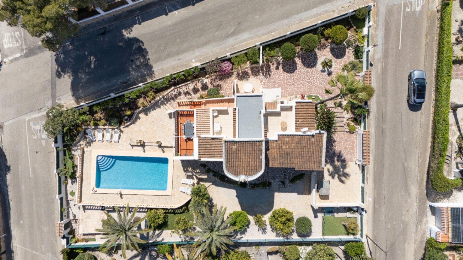 Vista aérea cenital de la propiedad que muestra la parcela de 1030 m², la piscina rectangular con solárium, las terrazas y el diseño del jardín mediterráneo con palmeras.
