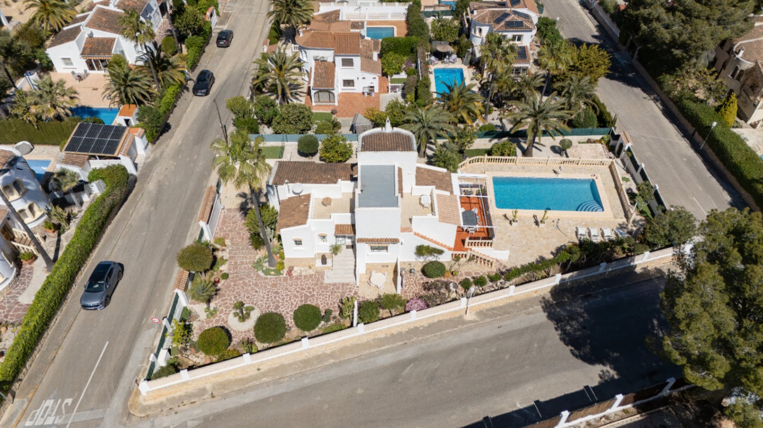 Vista aérea de la propiedad en parcela de esquina, destacando la piscina privada, amplias terrazas pavimentadas y jardines mediterráneos integrados en Pinosol.