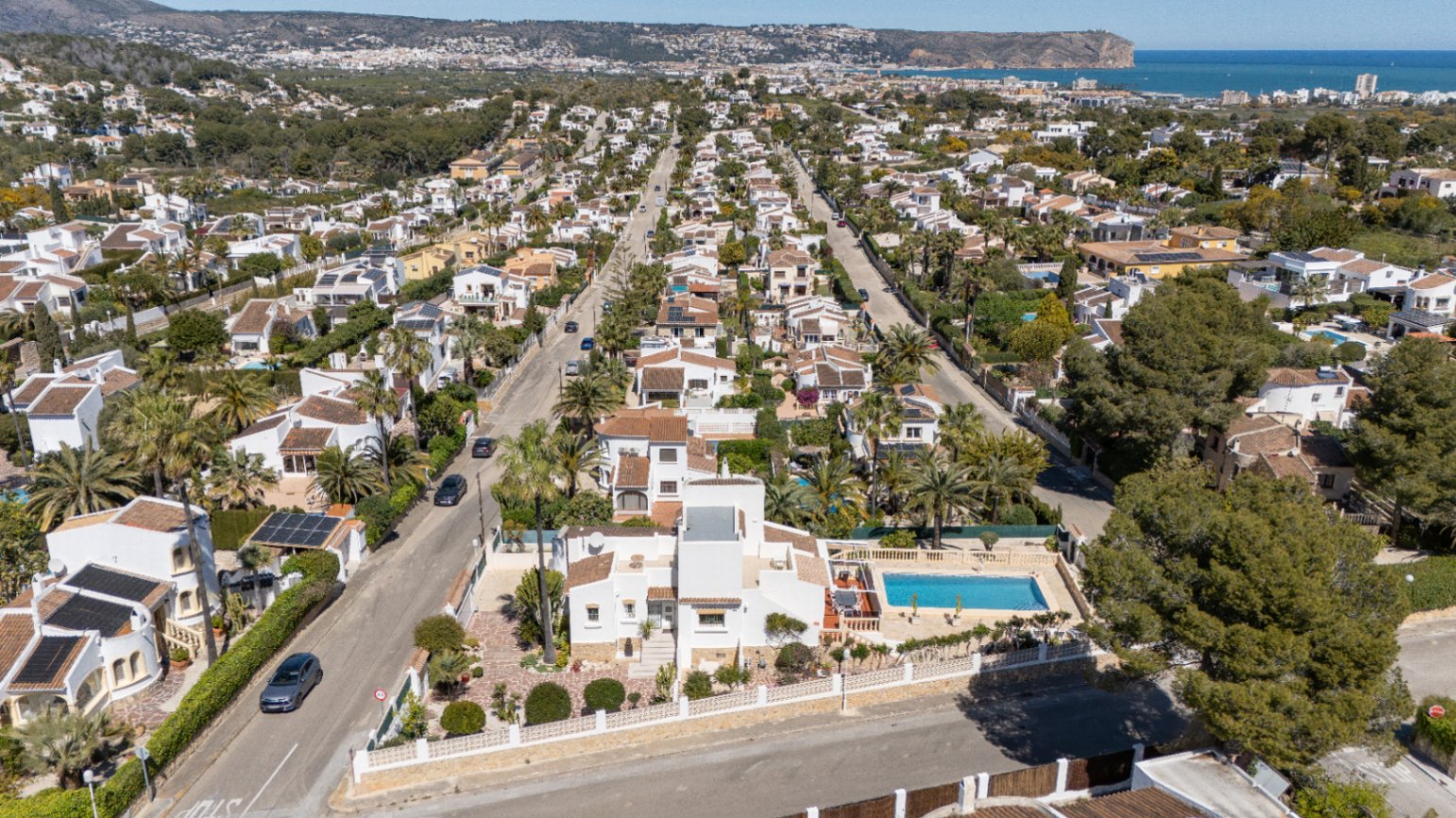 Vista aérea que muestra la ubicación del chalet en Pinosol, con su piscina privada y la cercanía a la costa de Jávea y el mar Mediterráneo al fondo.