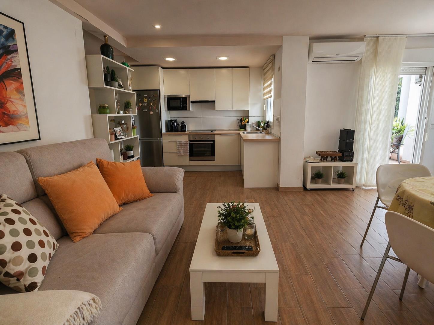 Salón-comedor de concepto abierto con suelos de gres efecto madera, cocina moderna integrada con electrodomésticos y acceso directo a la terraza exterior.