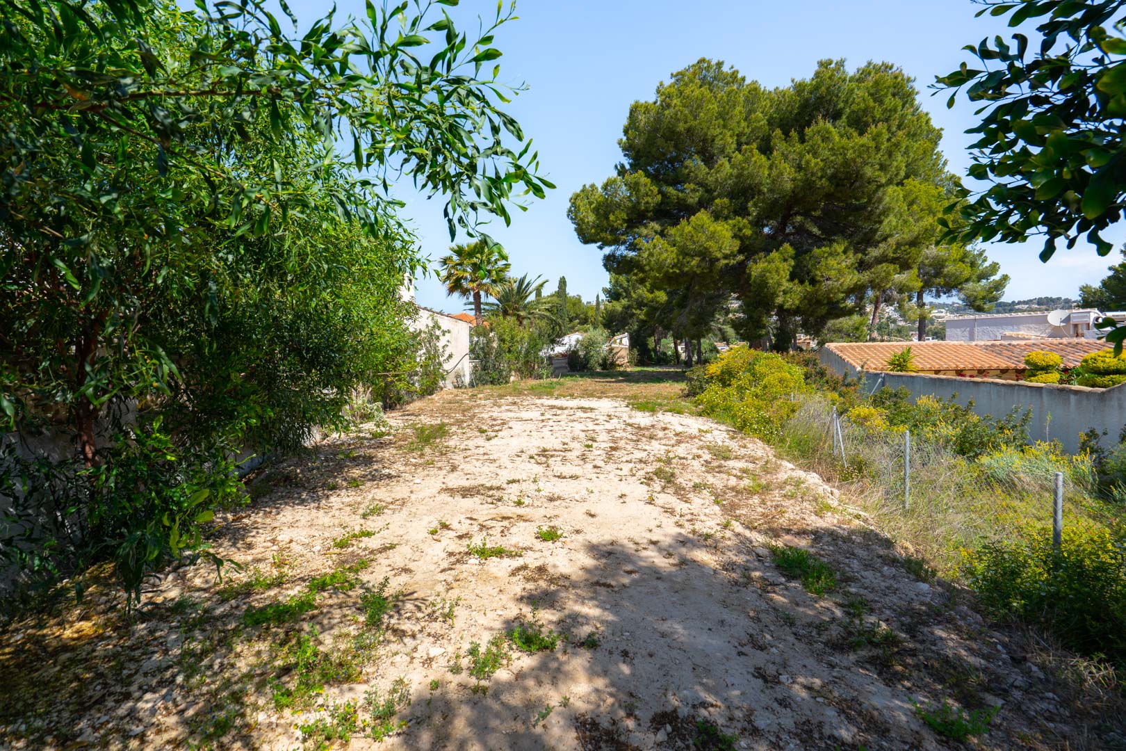 Amplia parcela llana de 900 m2 situada en la parte posterior de la villa, rodeada de vegetación y pinos, ideal para proyectos personalizados o zonas deportivas.