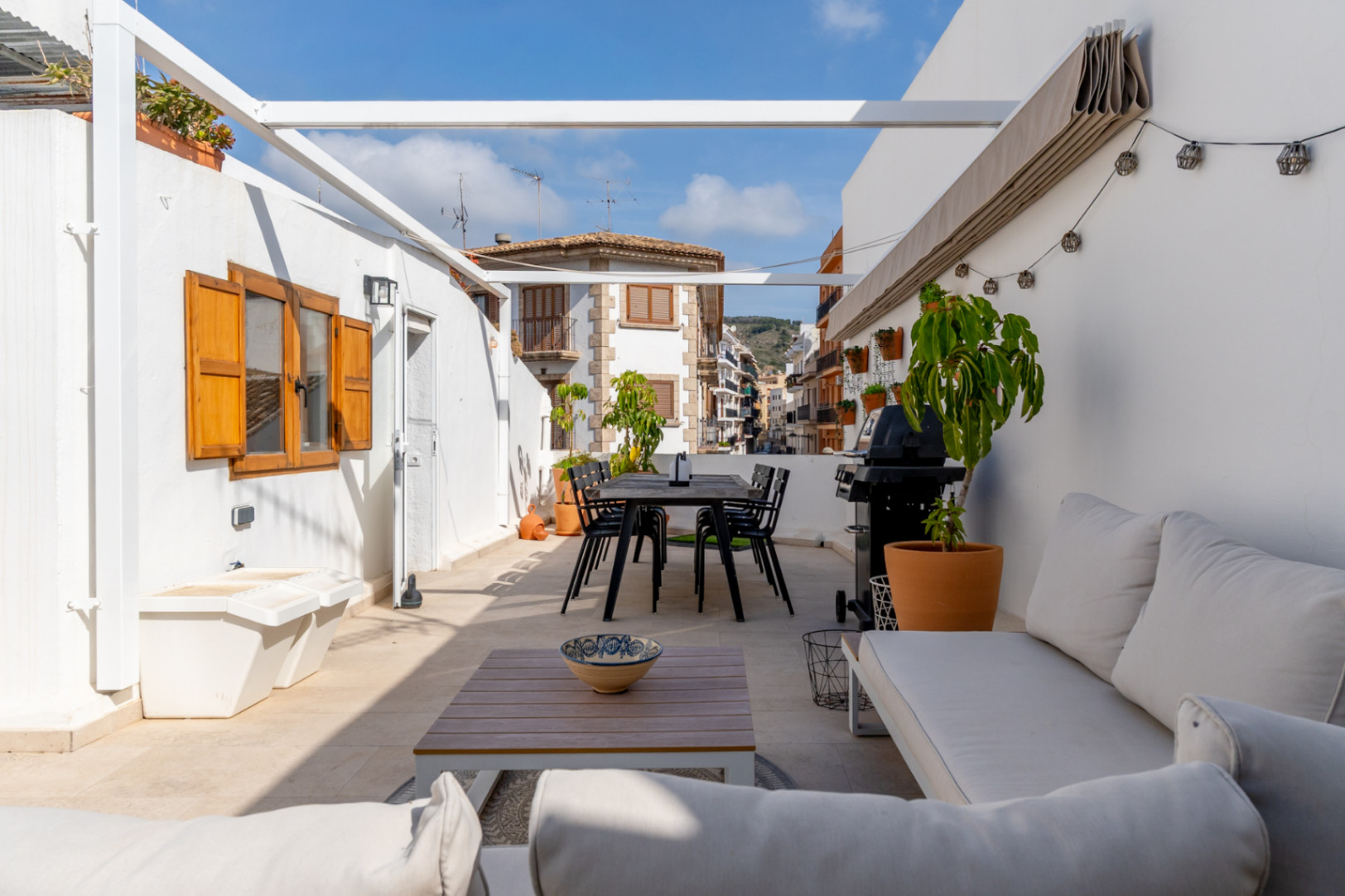 Amplia terraza privada con comedor y barbacoa, con vistas al casco antiguo de Jávea.