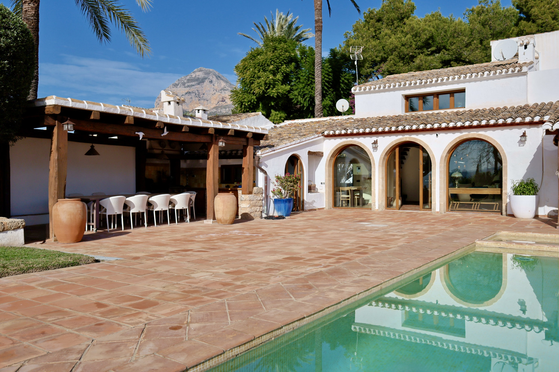 Vista de la terraza con piscina y comedor exterior cubierto en Jávea.