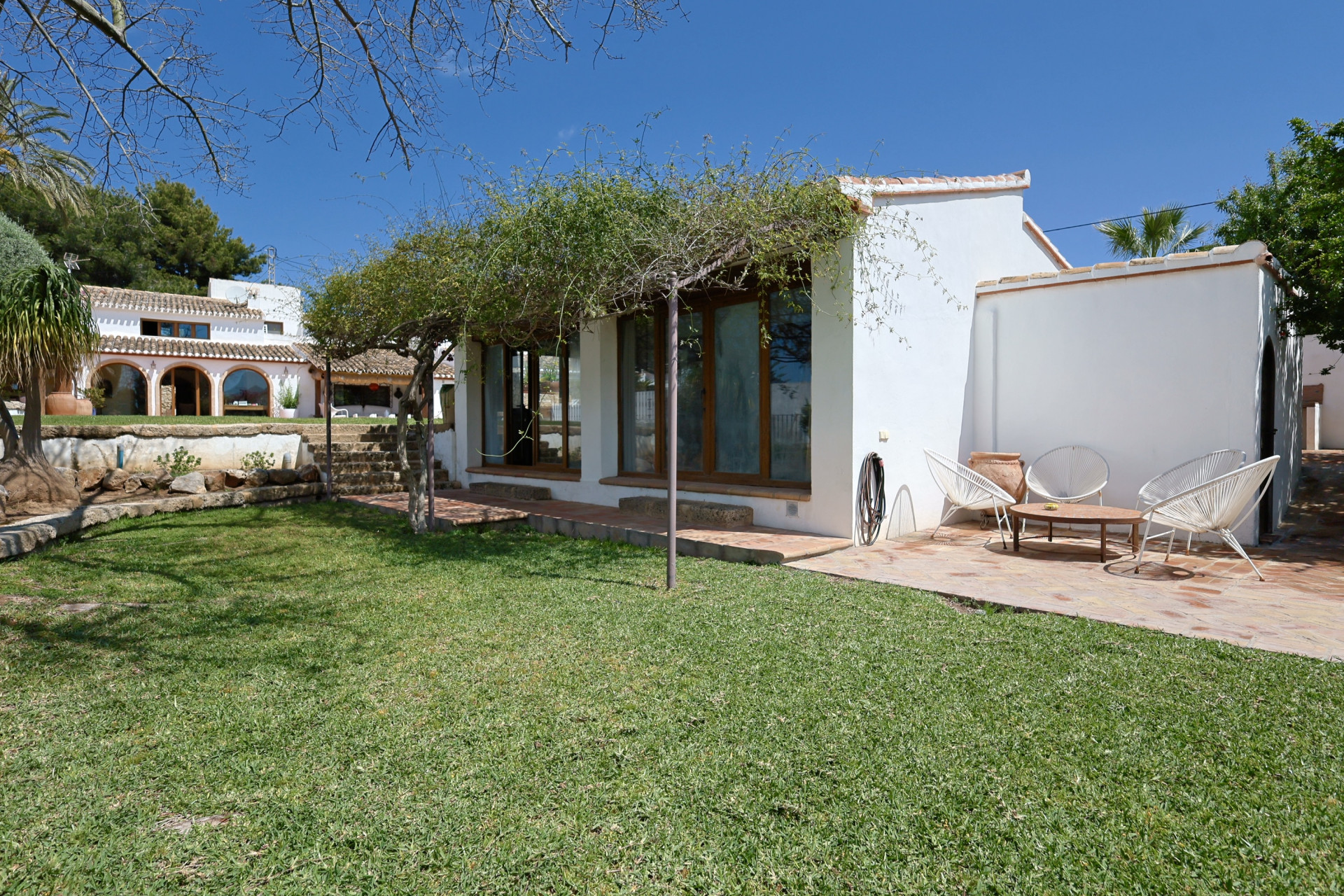 Vista del jardín con césped y terraza con mobiliario exterior en villa de Jávea.