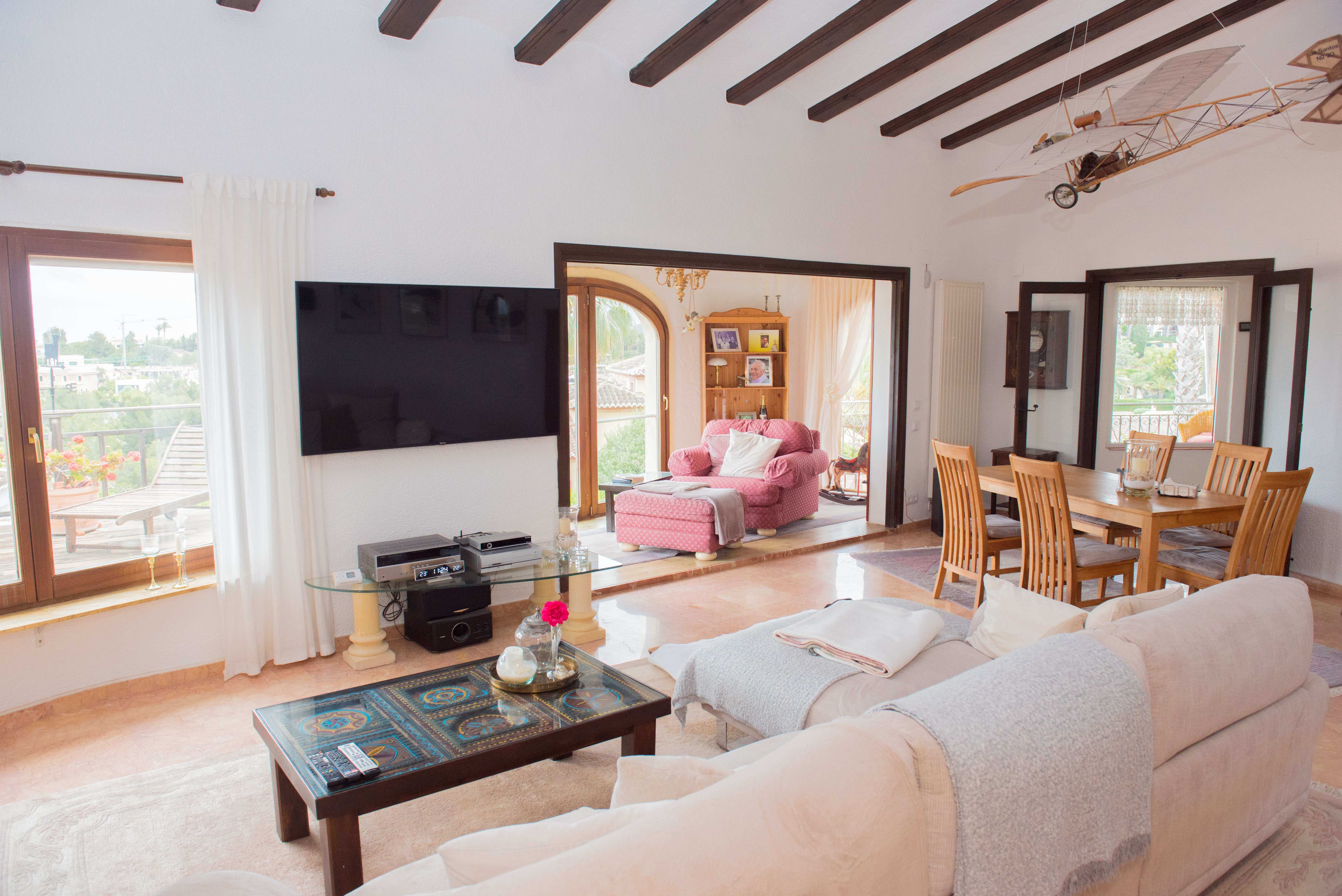 Salón comedor con vigas de madera vista, suelos de mármol y acceso directo a la terraza. Incluye una zona de estar amplia y un comedor formal con vistas despejadas.