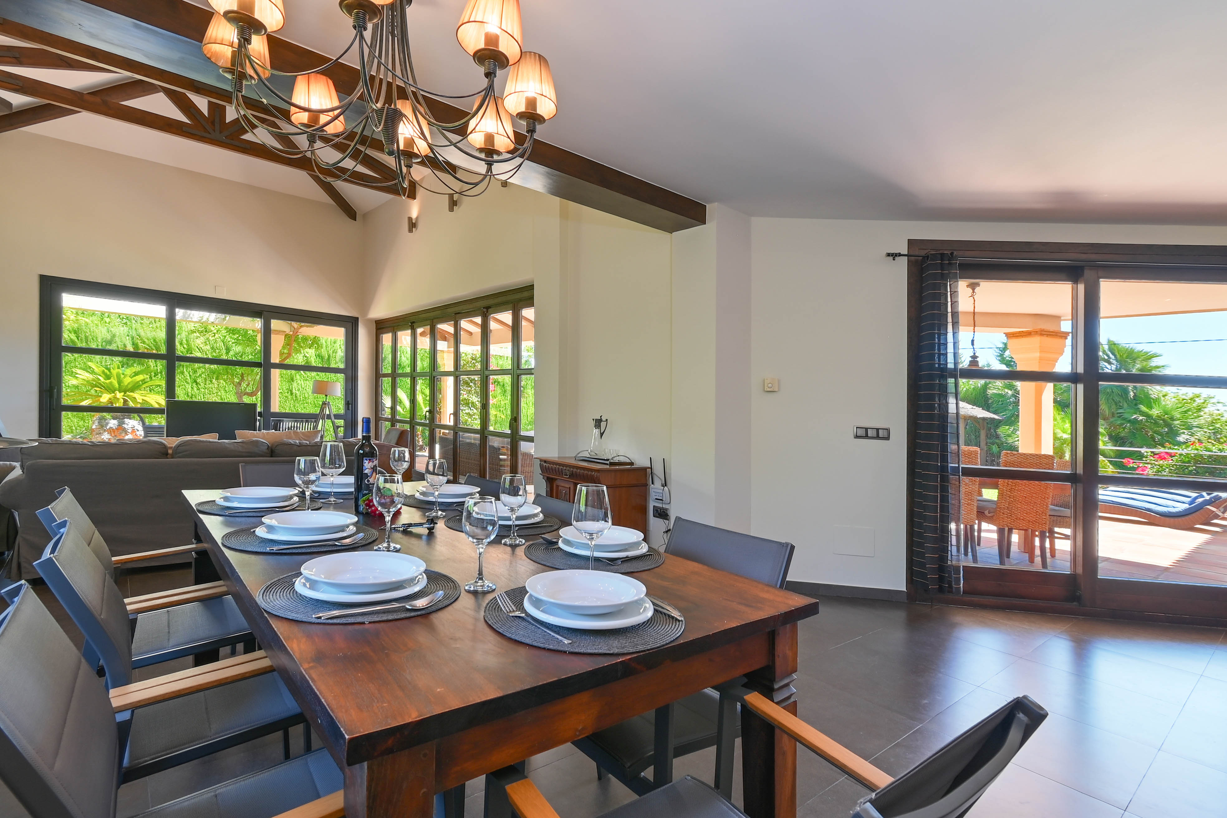 Comedor luminoso con mesa de madera oscura y vistas a la terraza con piscina.