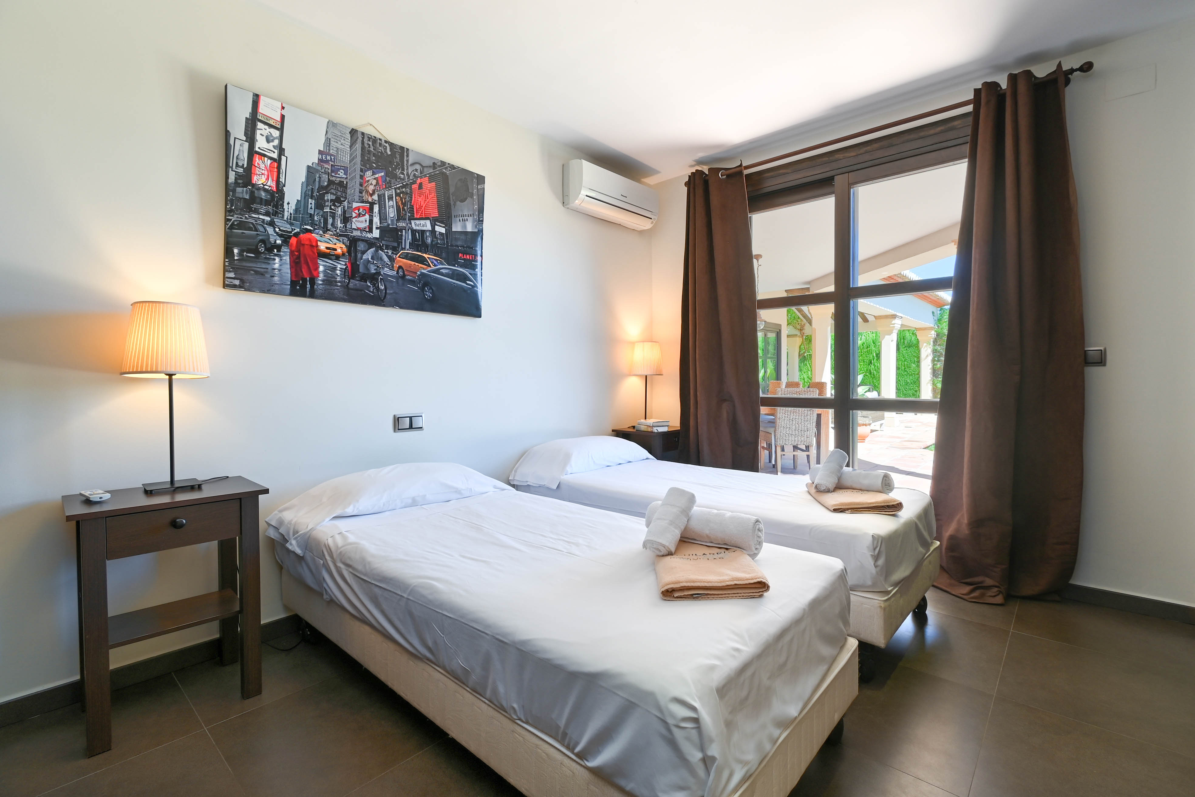 Dormitorio con dos camas individuales, ropa de cama blanca y vista al exterior.