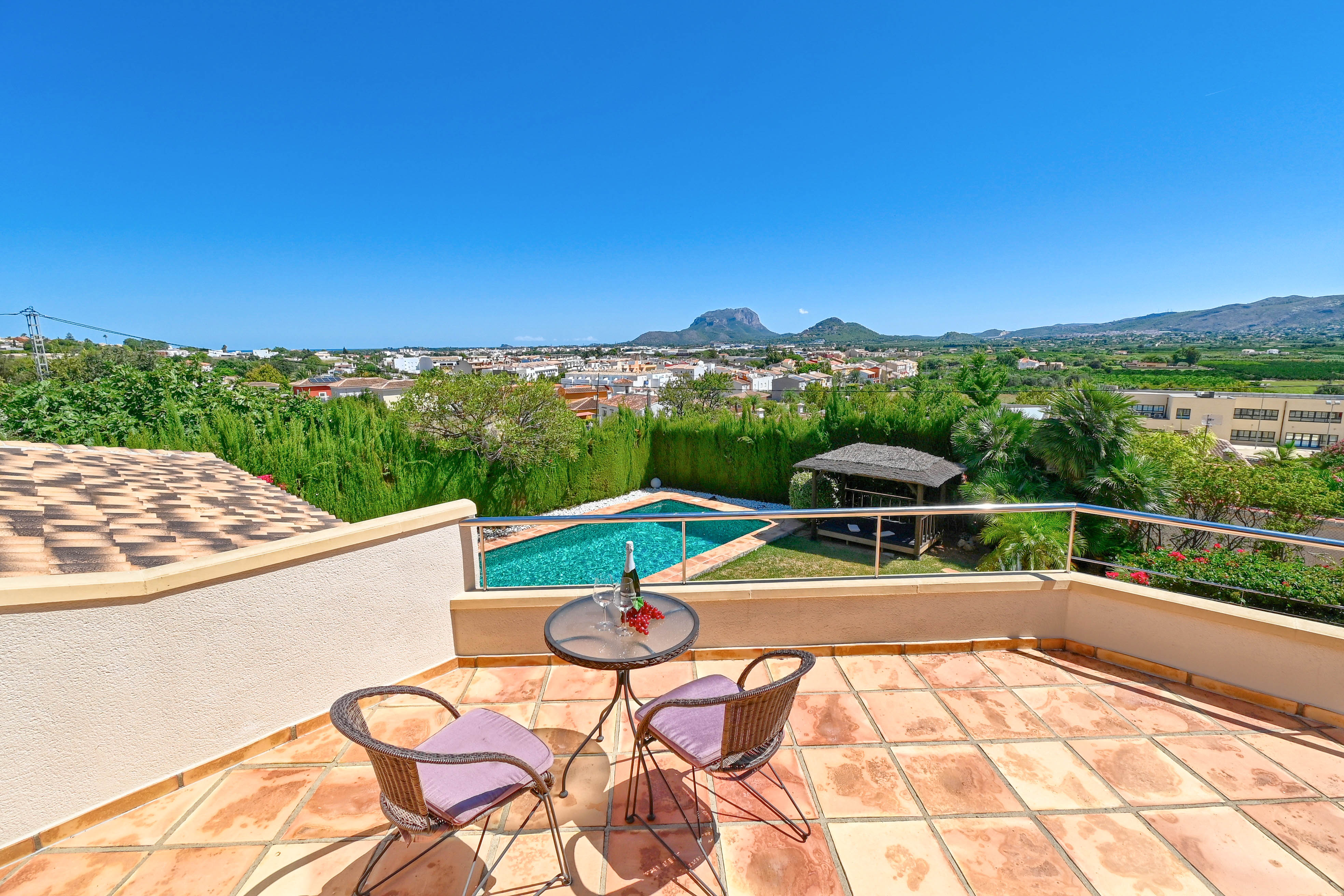 Terraza con mesa de bistro, vistas a la piscina y al paisaje montañoso de Denia.