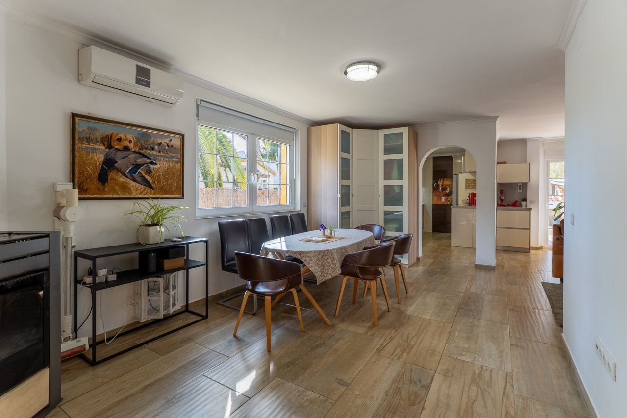 Comedor luminoso con suelo de madera y mesa ovalada con seis sillas de cuero marrón.