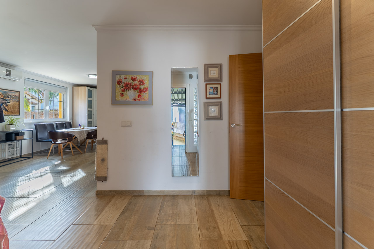 Entrada luminosa con suelo de cerámica imitación madera y decoración mural.