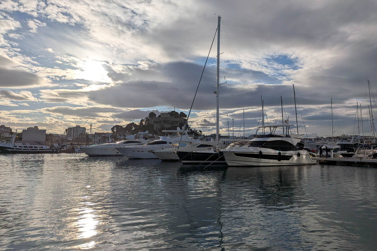 Vista del puerto deportivo con yates y reflejos del sol en el agua.