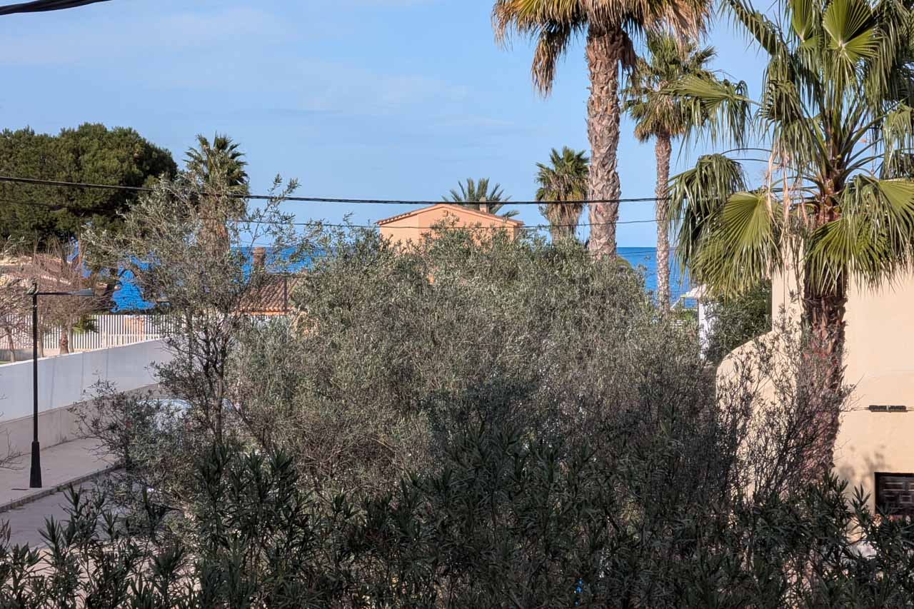 Vista parcial de la vivienda con vegetación mediterránea y el mar al fondo.