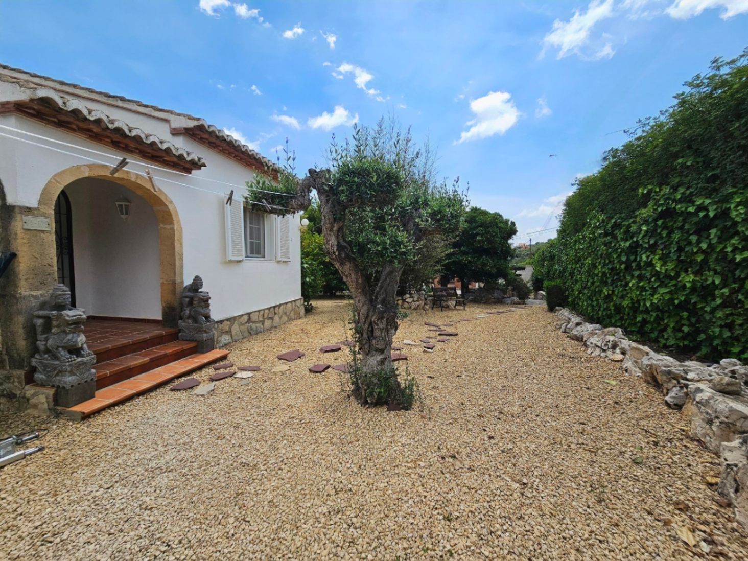 Entrada a la villa con grava, escalones de terracota y arco de piedra arenisca.