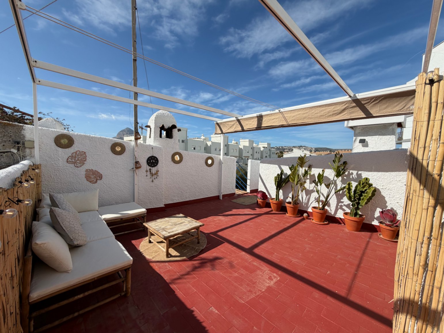 Terraza con suelo de terracota, mobiliario de bambú y decoración mural artesanal.