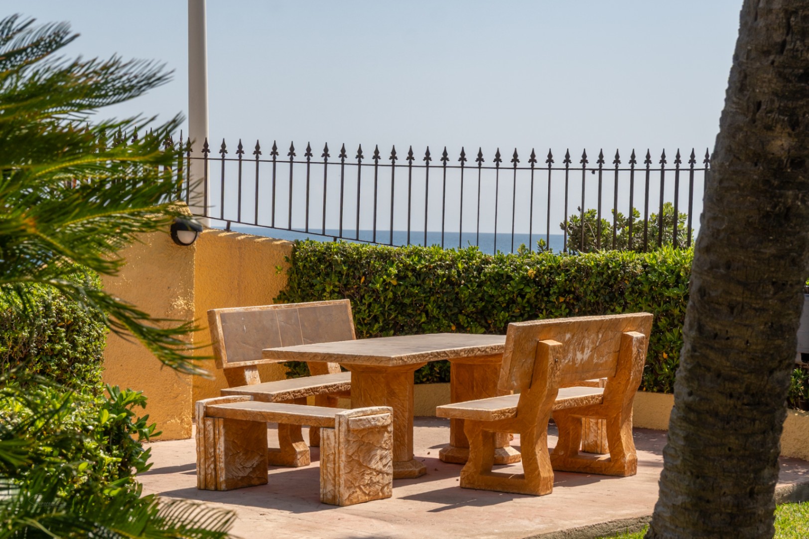 Patio con mesa de piedra y vistas al mar en urbanización ajardinada de Jávea.