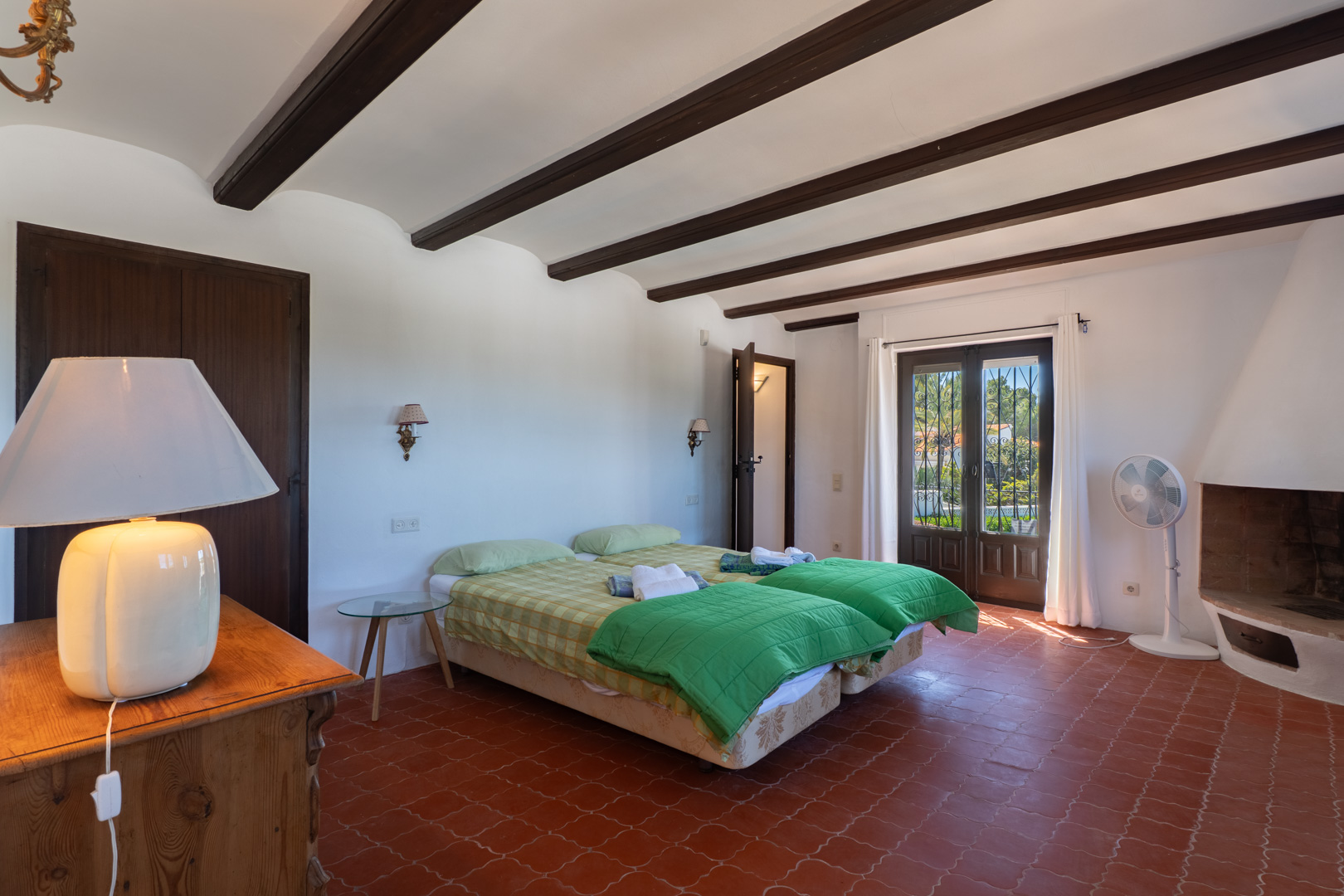 Dormitorio con camas individuales, vigas de madera y suelo de terracota.